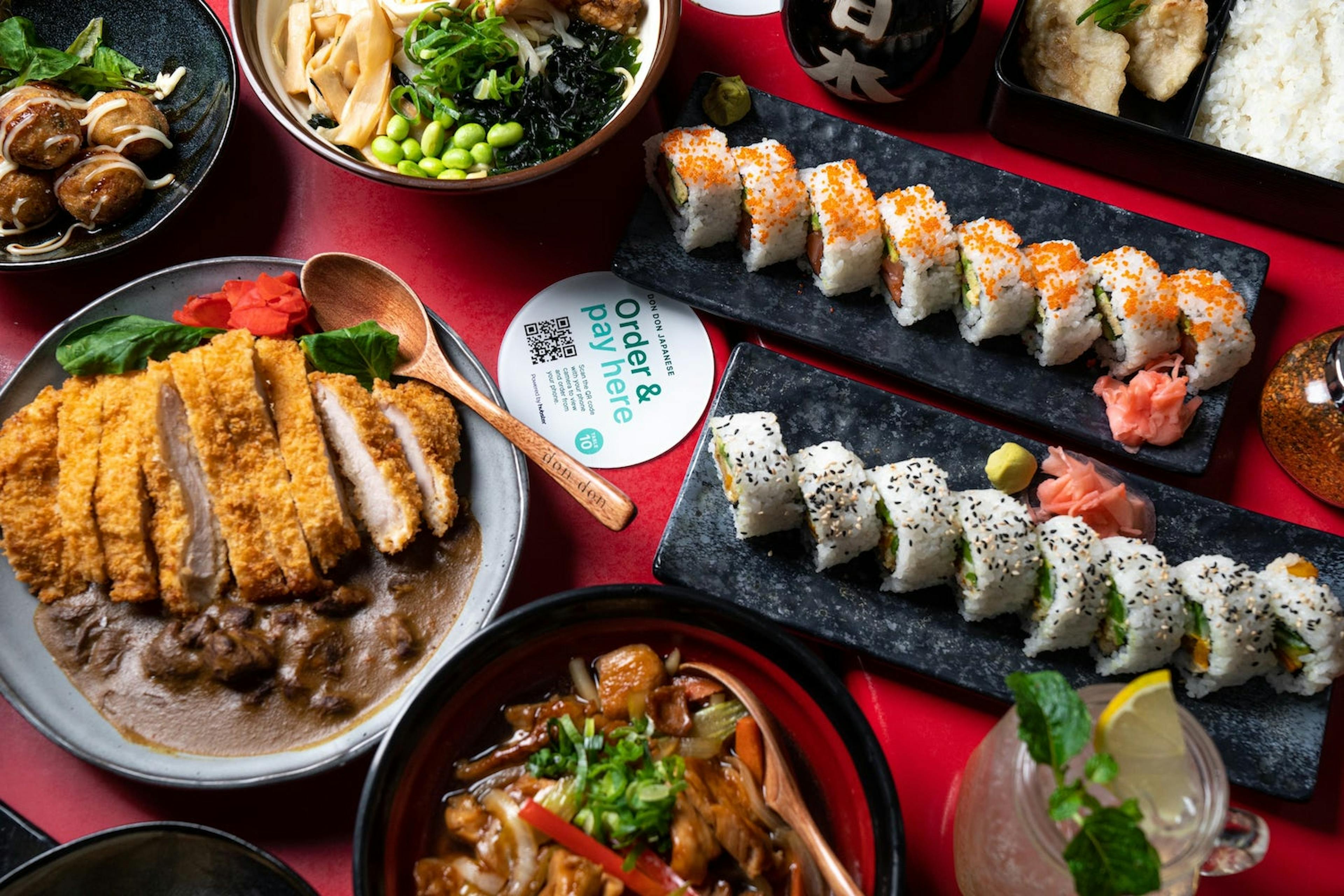 Image of a table filled with Japanese food with a QR code ordering coaster in the center