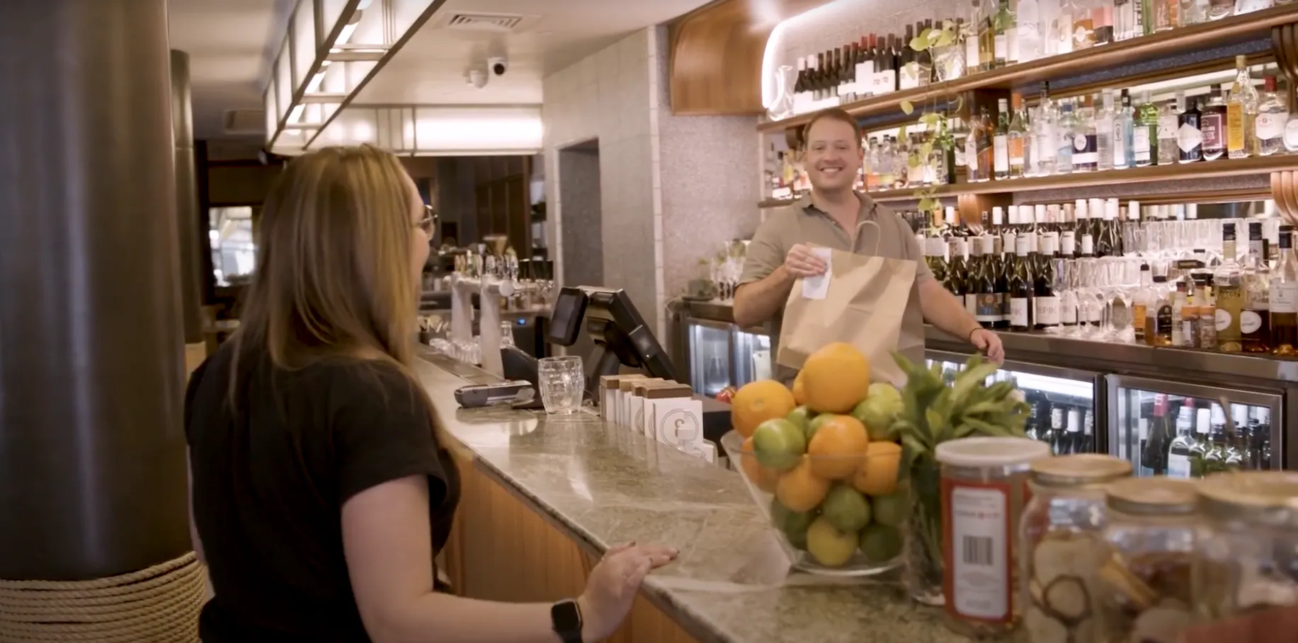 Image of a woman collecting a takeaway bag over the counter at Hotel Rose Bay