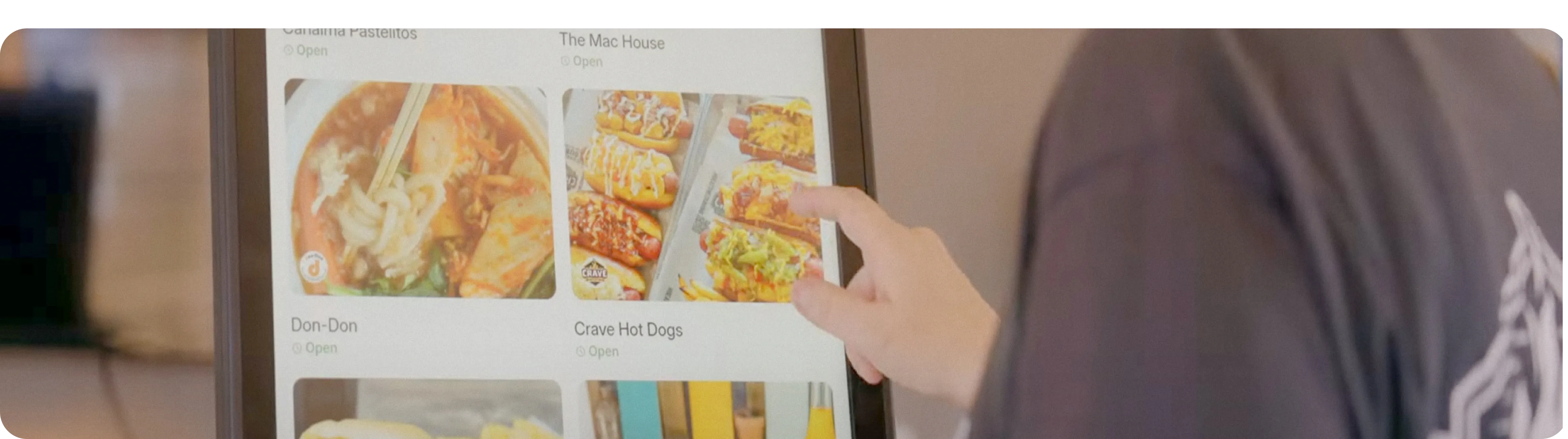 Customer selecting a menu item on a restaurant self-order kiosk touchscreen