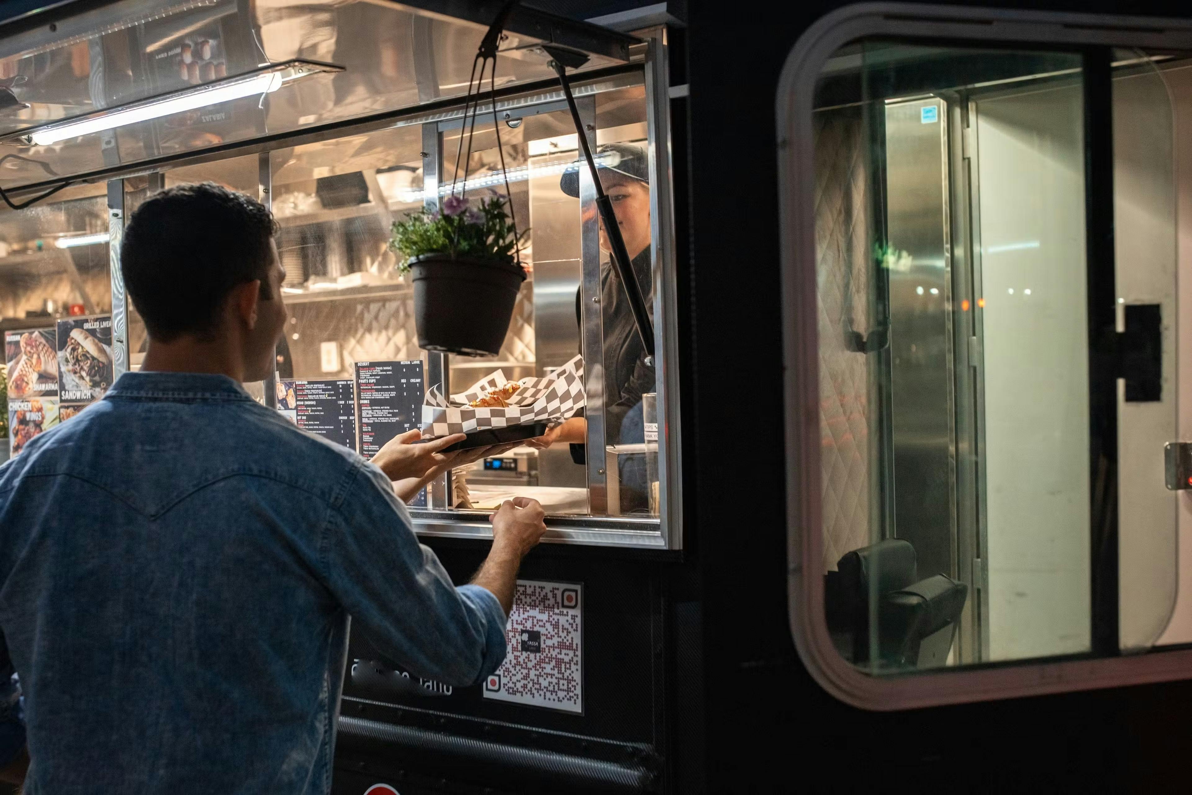 Man picking up a hotdog from a food truck