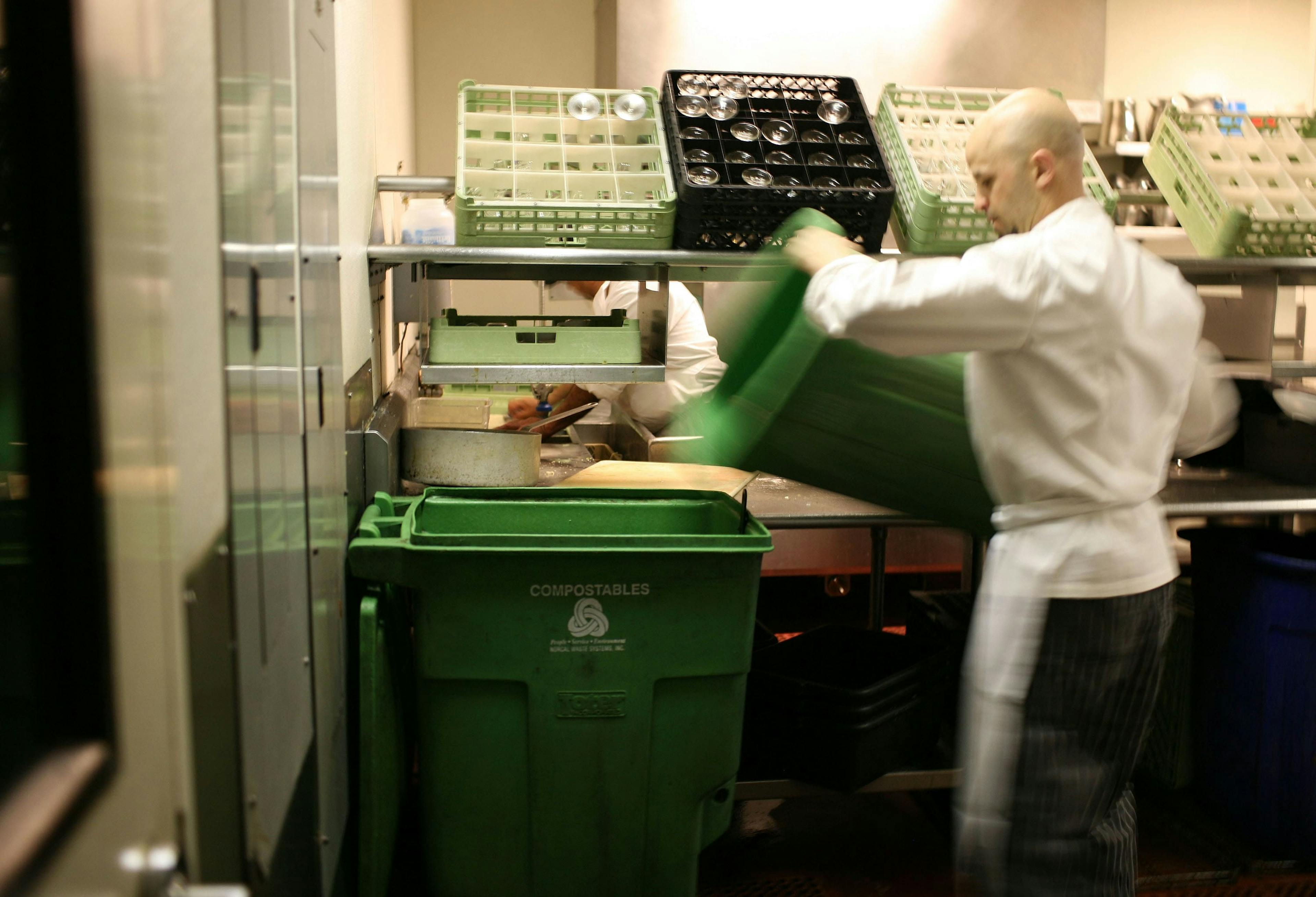 Image of a restaurant employee transferring food scraps into a compost bin