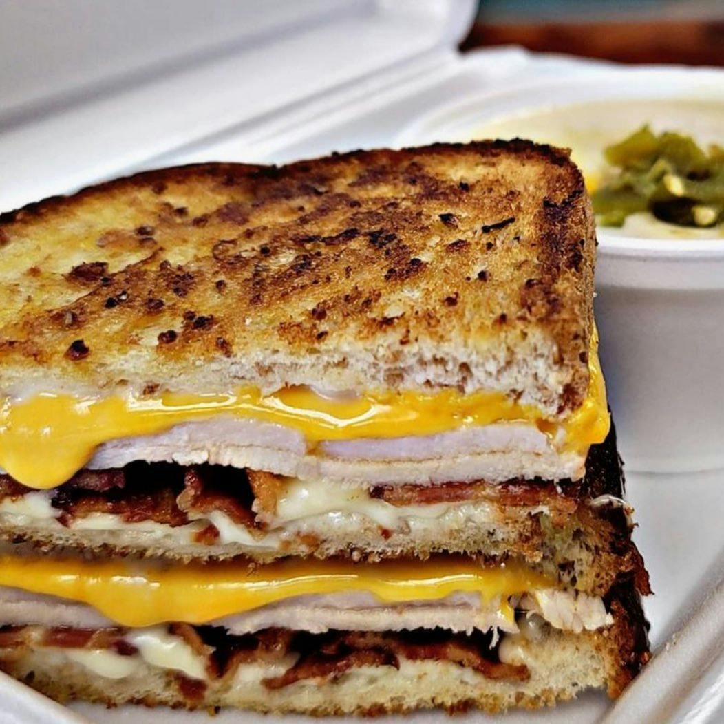 Image of a toasted turkey and cheese sandwich in a to-go container