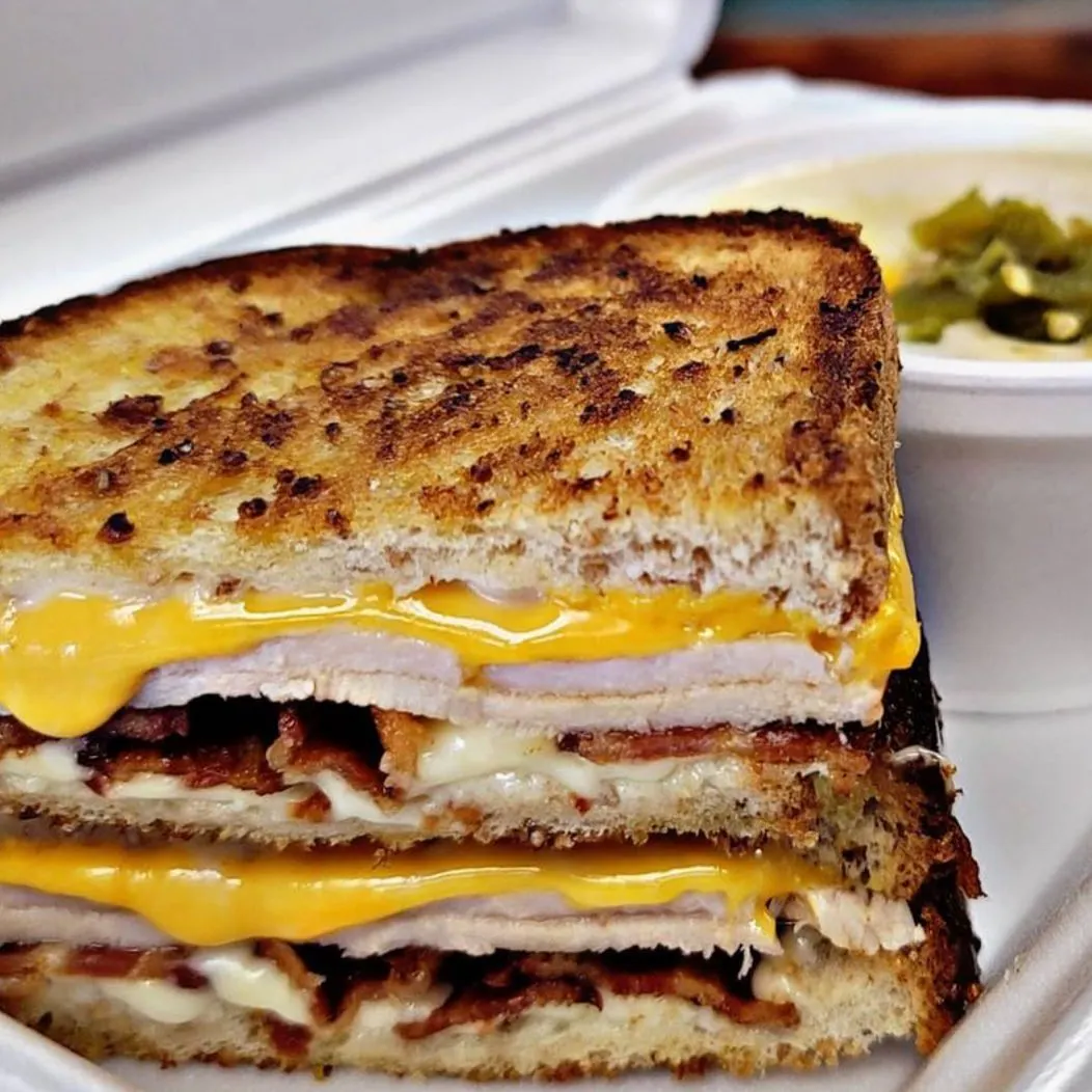 Image of a toasted turkey and cheese sandwich in a to-go container