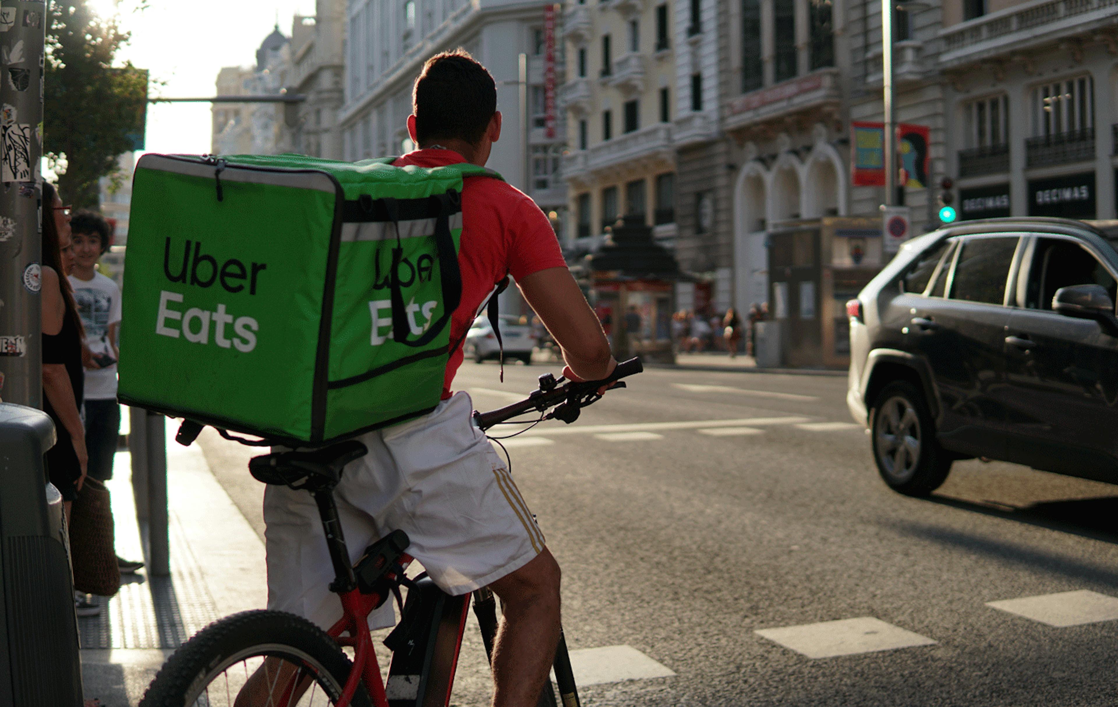 Image of an Uber Eats delivery courier dropping of an order on his bike