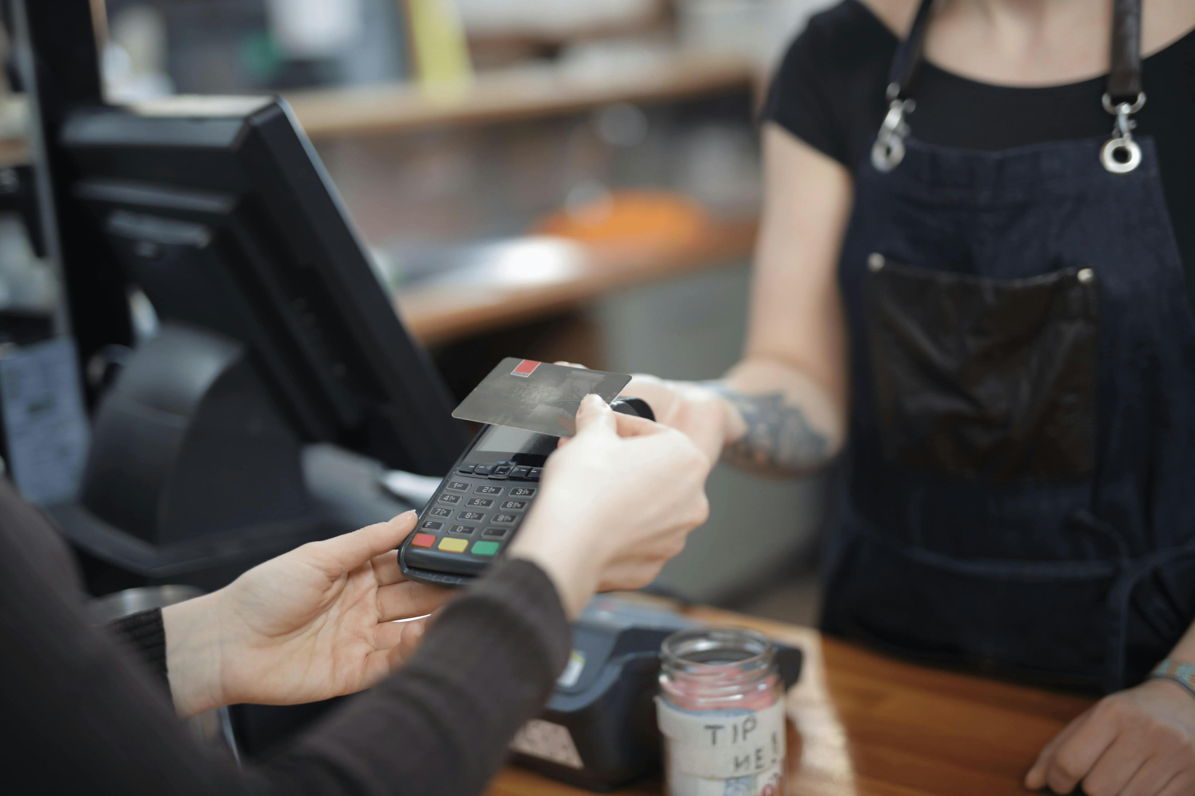 Image of a restaurant worker holding out a card reader so the customer can tap to pay