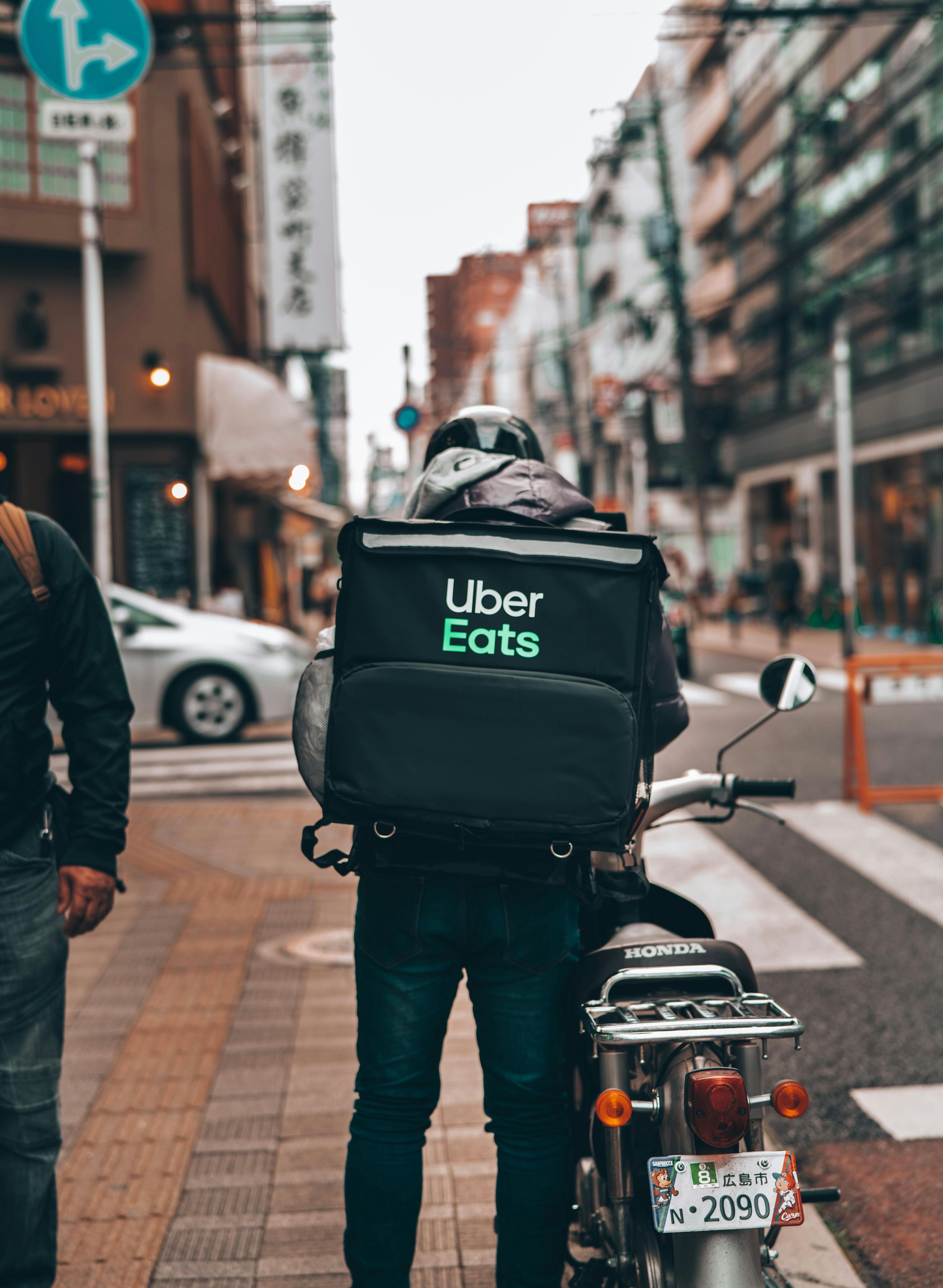 Image of Uber Eats courier getting on bike with delivery order in backpack.