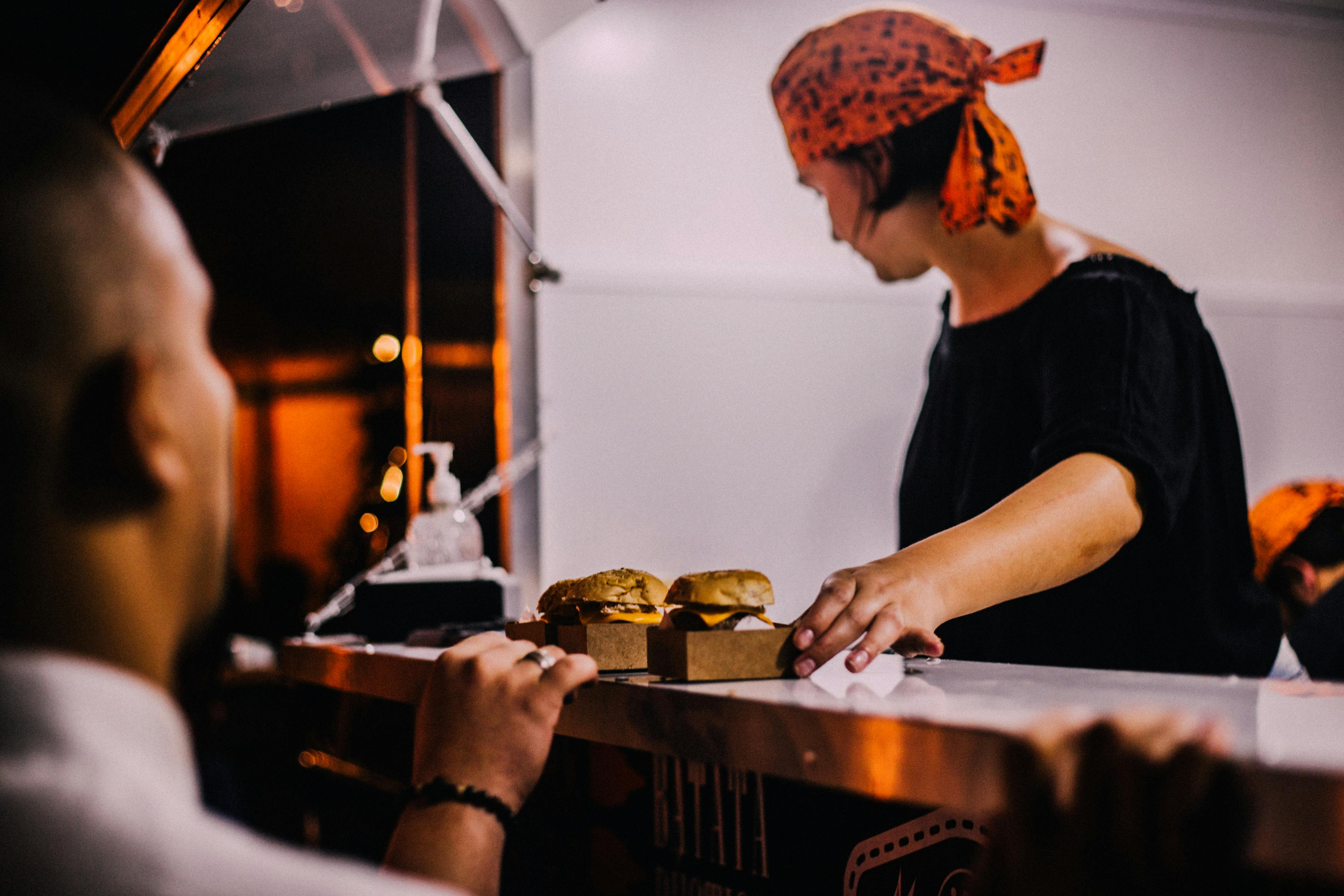 Food truck owner serving food with a POS system. 