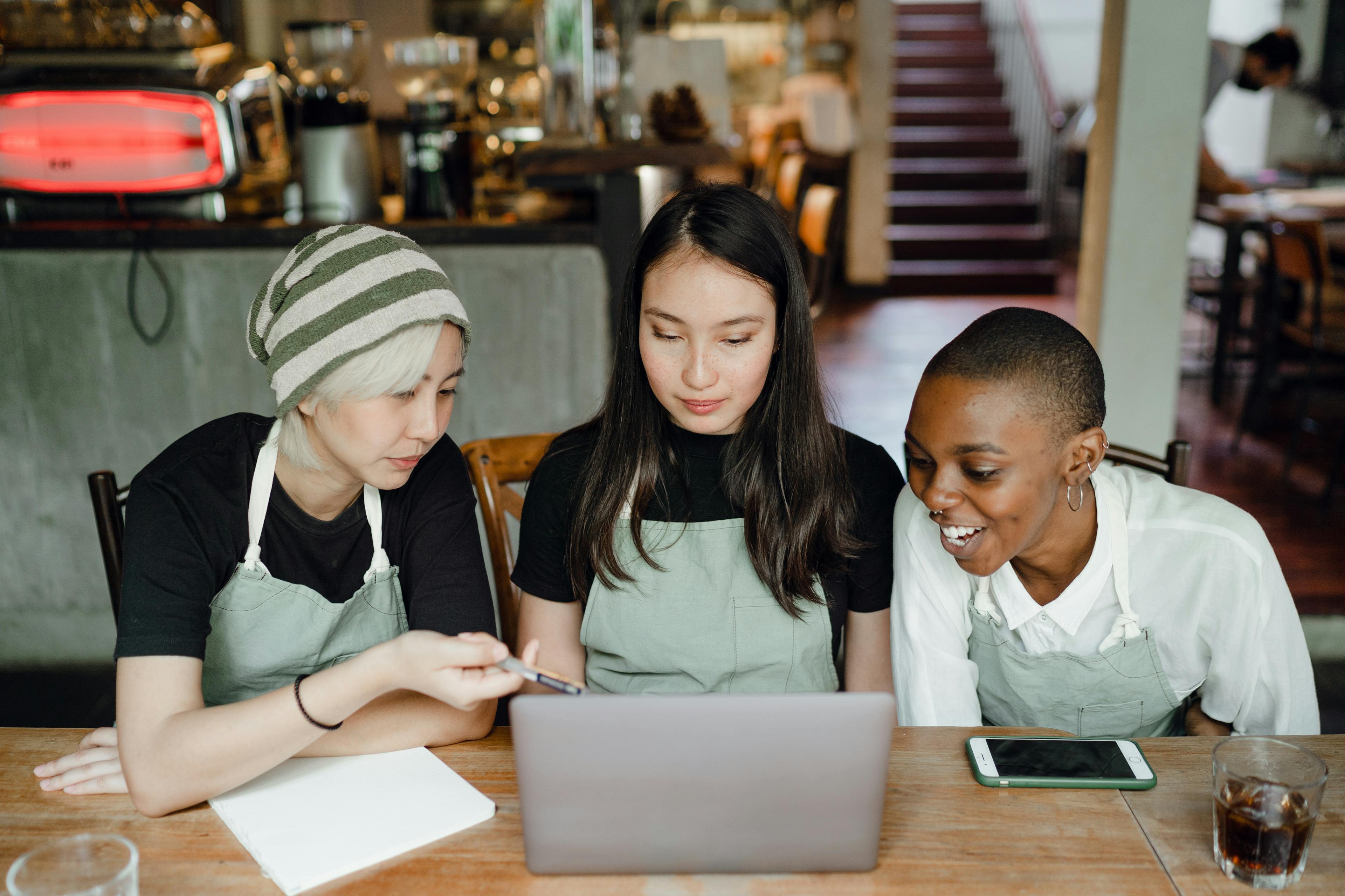 Image of three women working at a restaurant, looking at their sales on a computer.