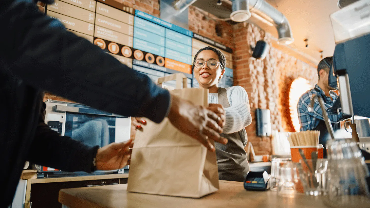 Image of a restaurant worker handing a customer a delivery order