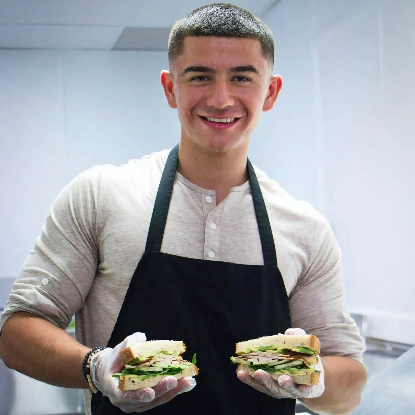 Image of Urbano Food Group employee holding up two sandwiches.