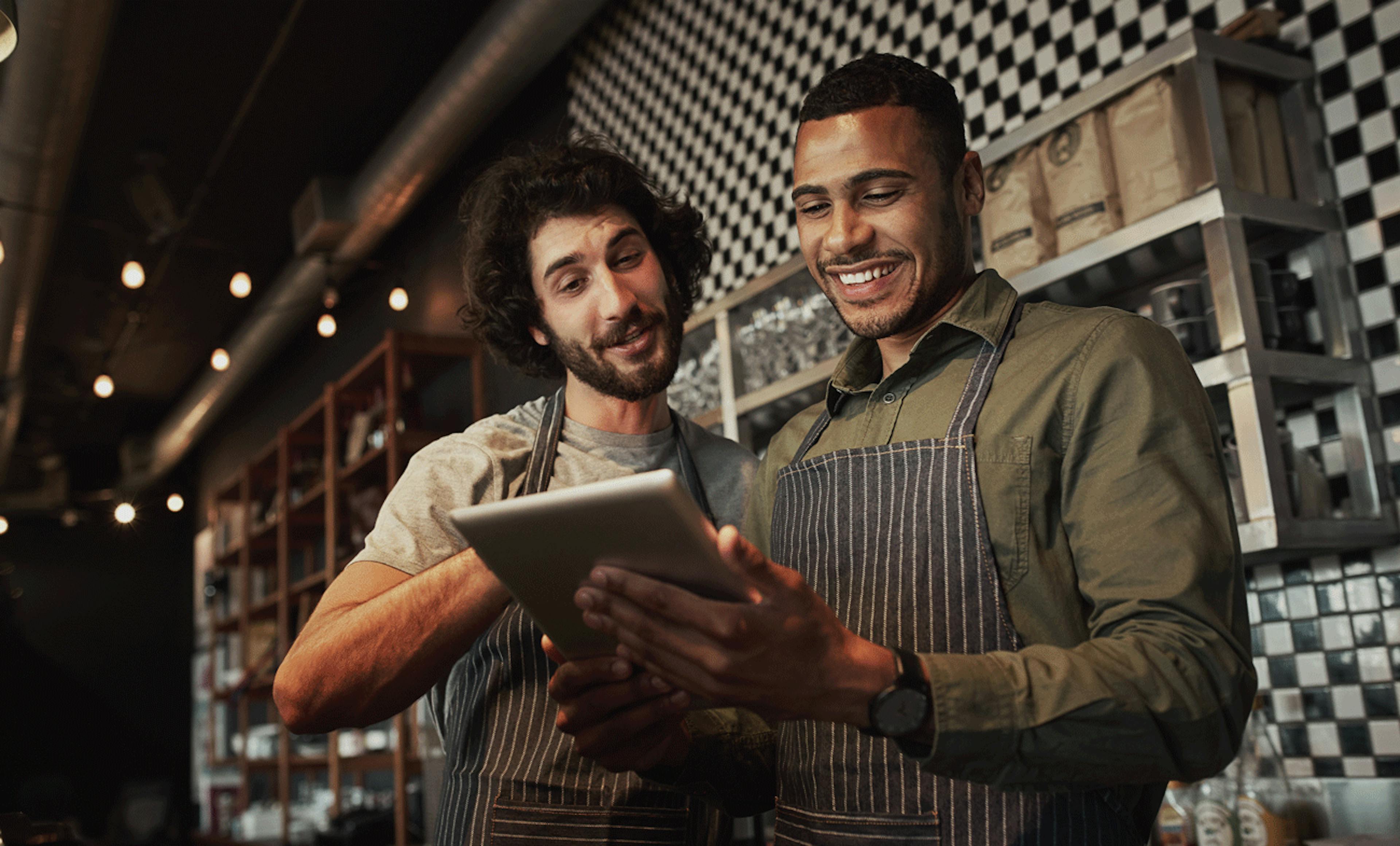 Image of two men working at a restaurant looking at their orders on a tablet