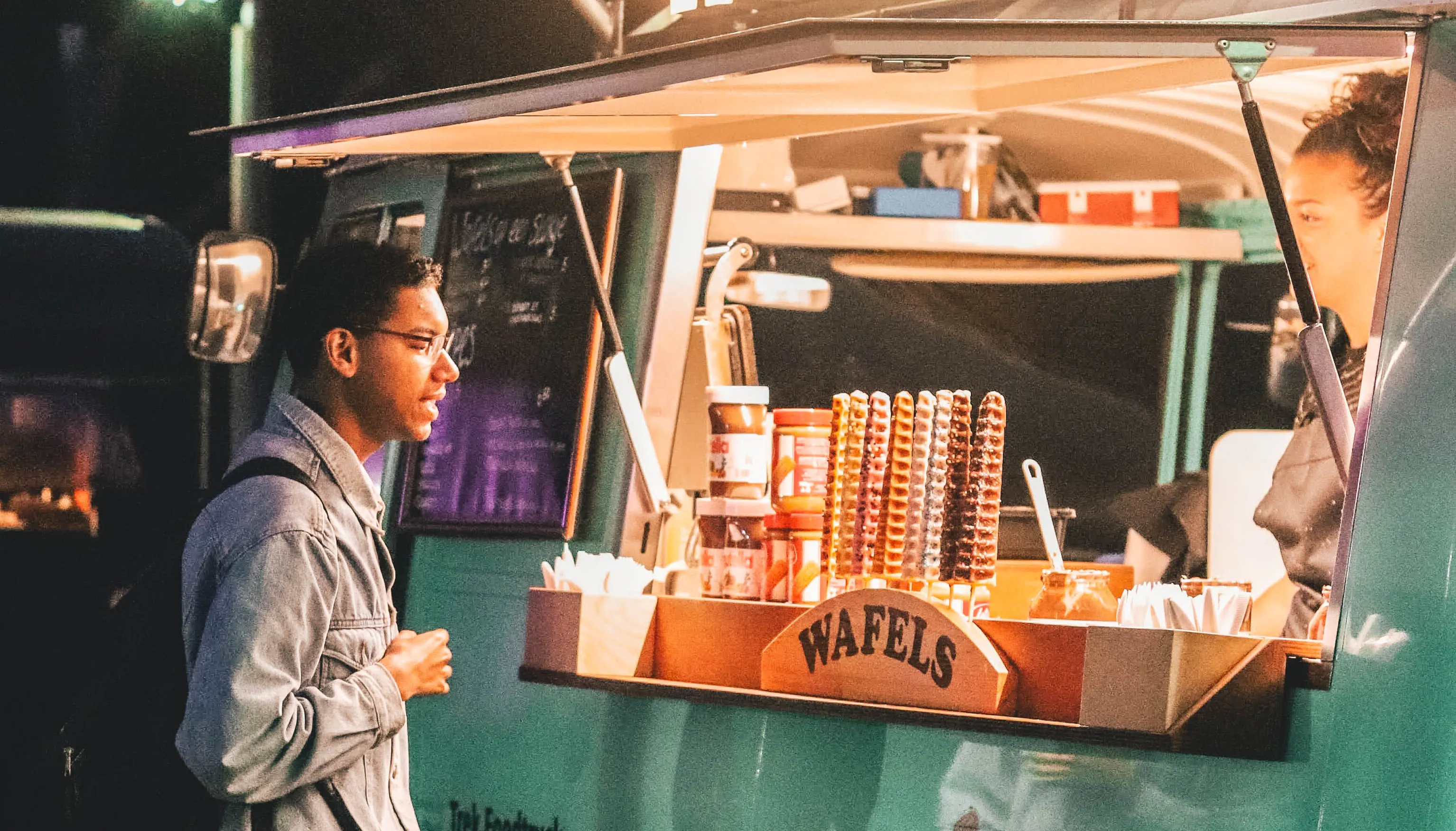 A delivery courier standing outside a food truck.