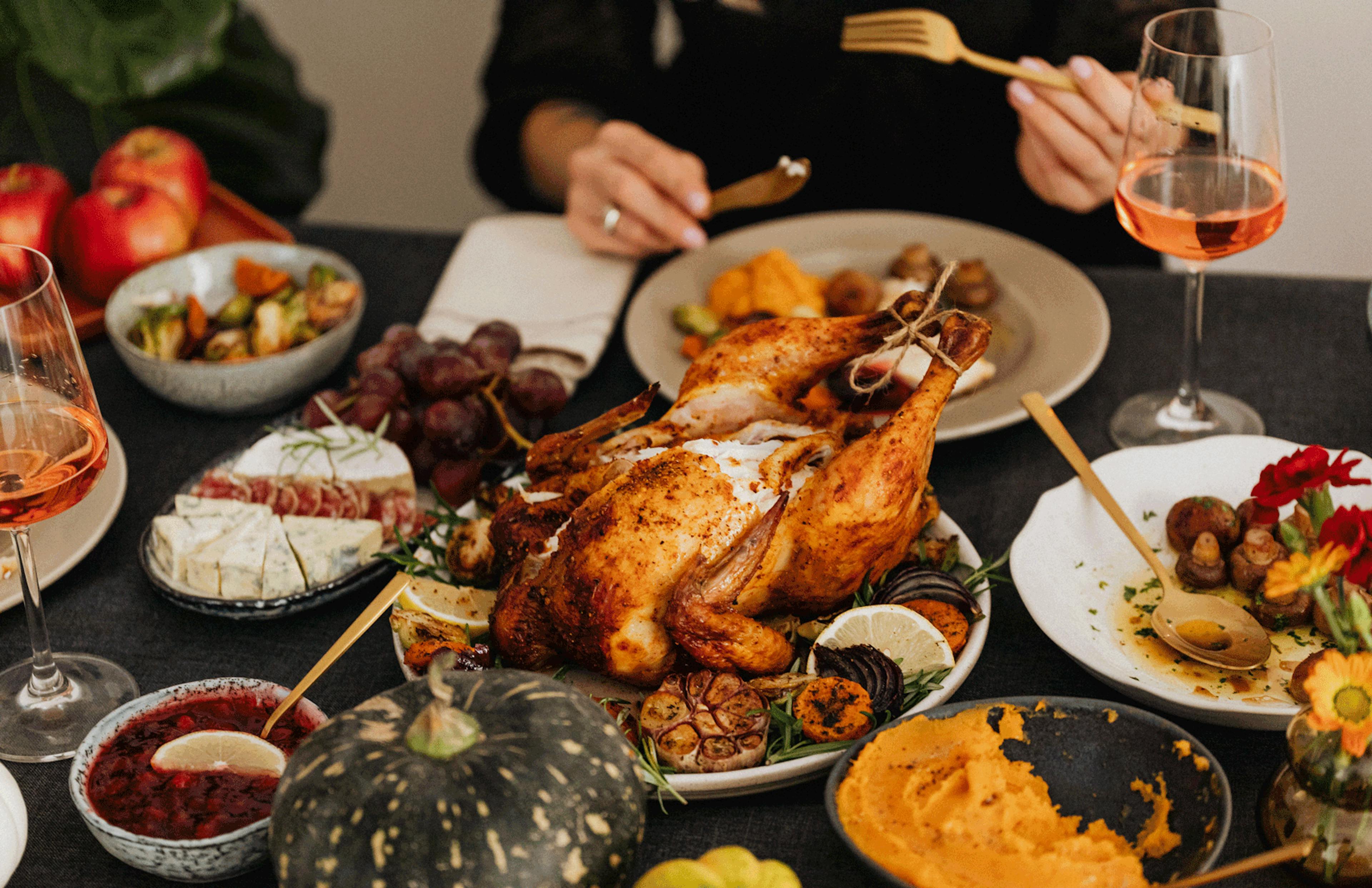 Image of a Thanksgiving tablescape with a turkey, sides, a gourd and more