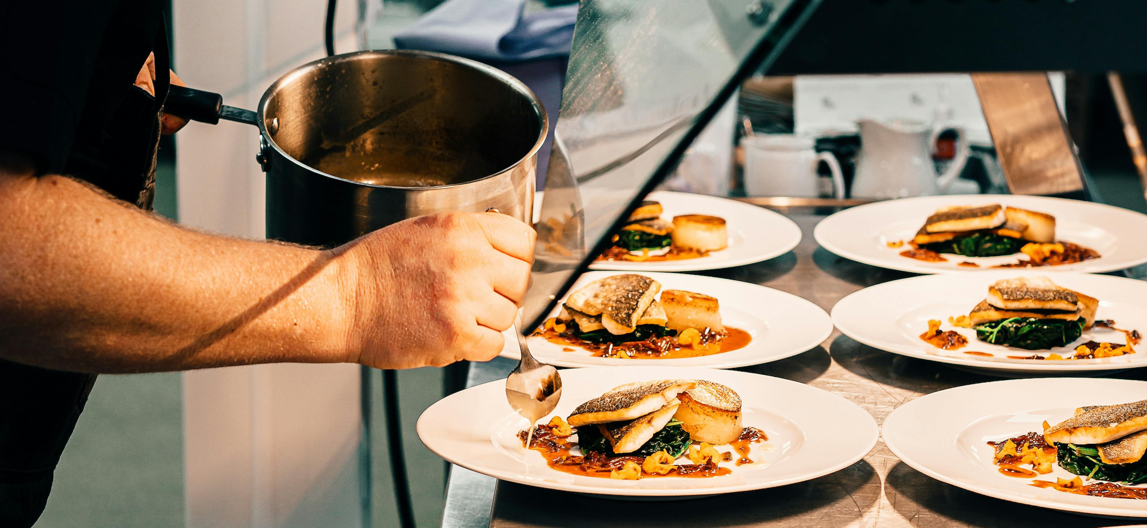 A chef dressing a plate in a restaurant. 