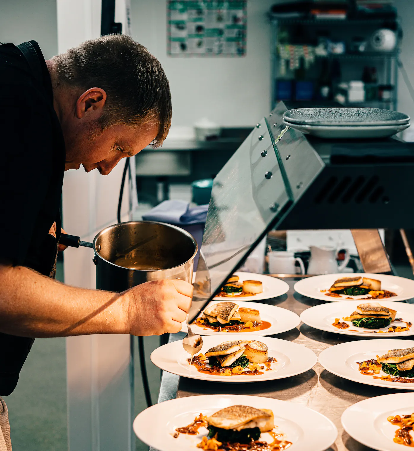 A chef dressing a plate in a restaurant.