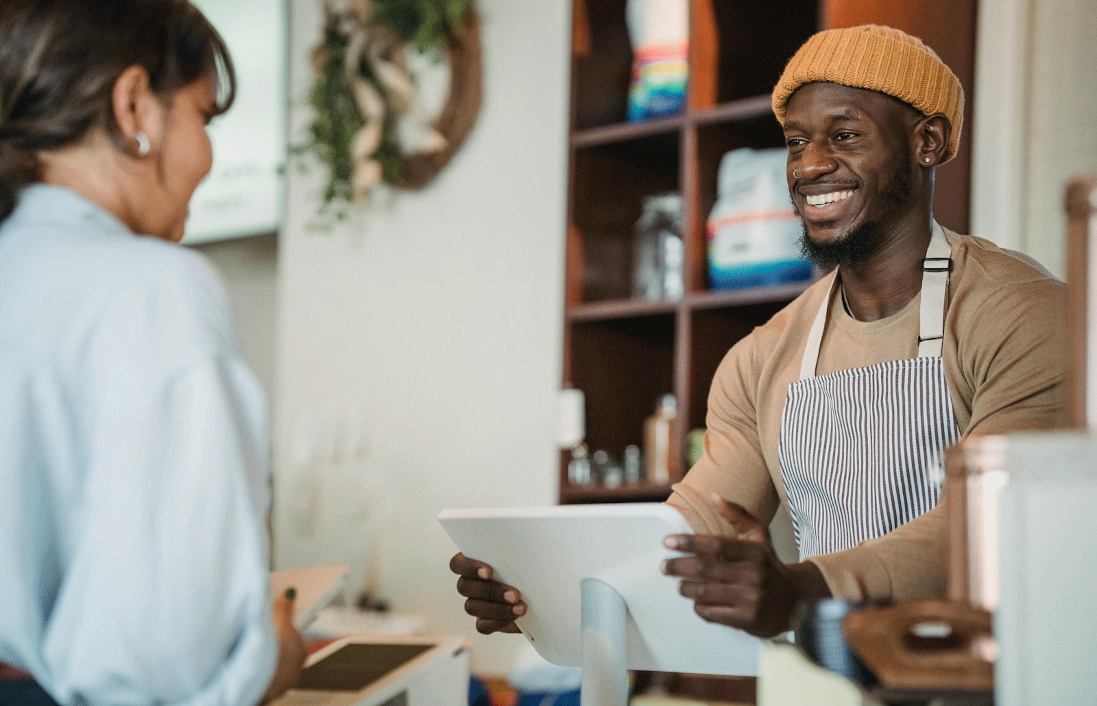 Restaurant employee smiling while helping a customer check out at the POS