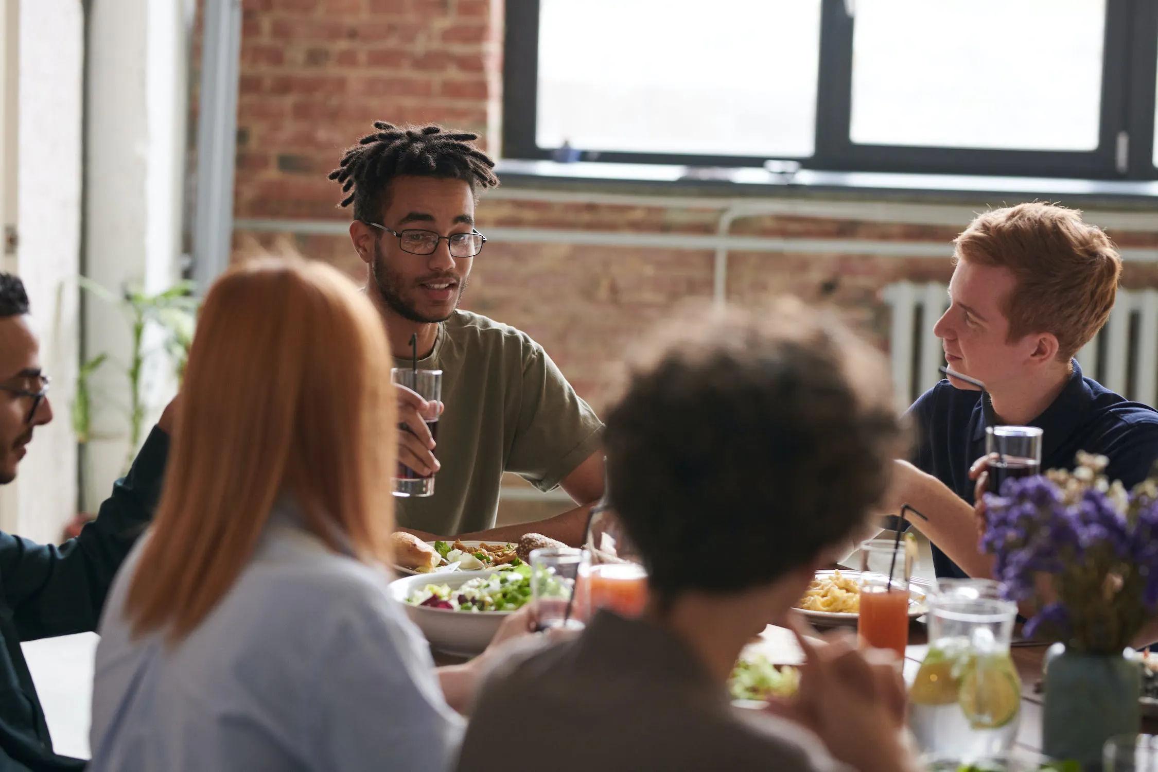 Group of Gen Z friends eating around a table.