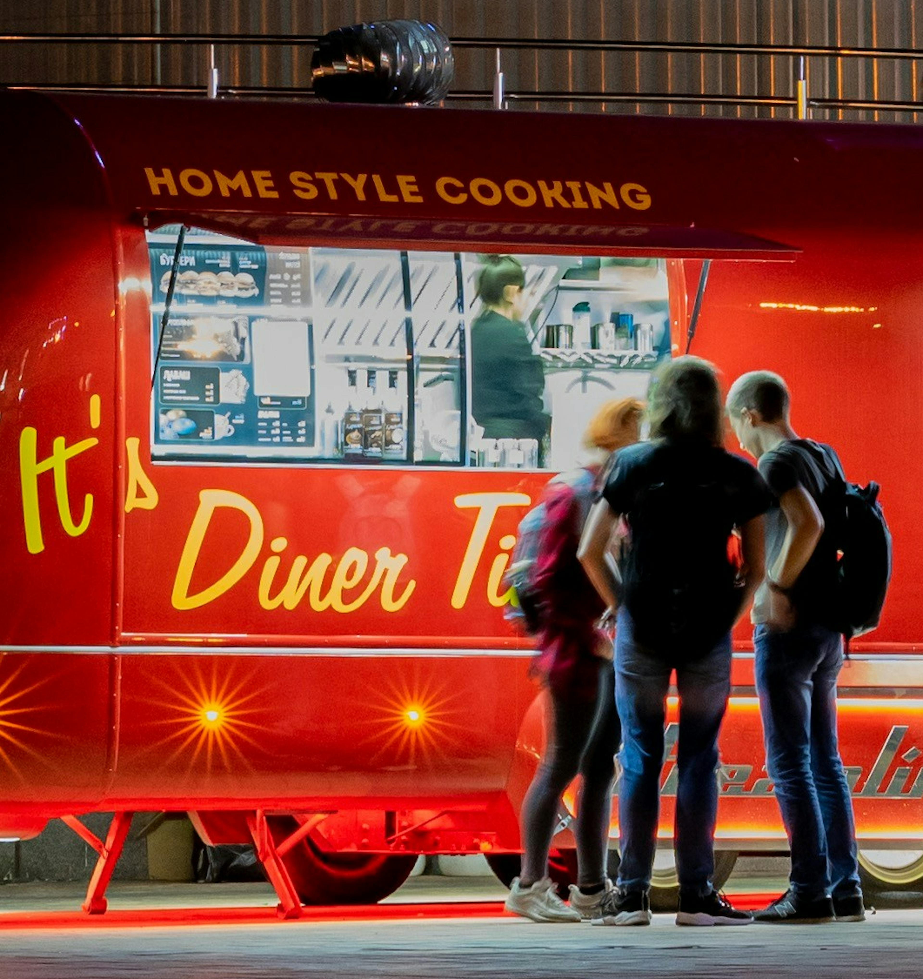 Some customers standing outside a profitable food truck. 