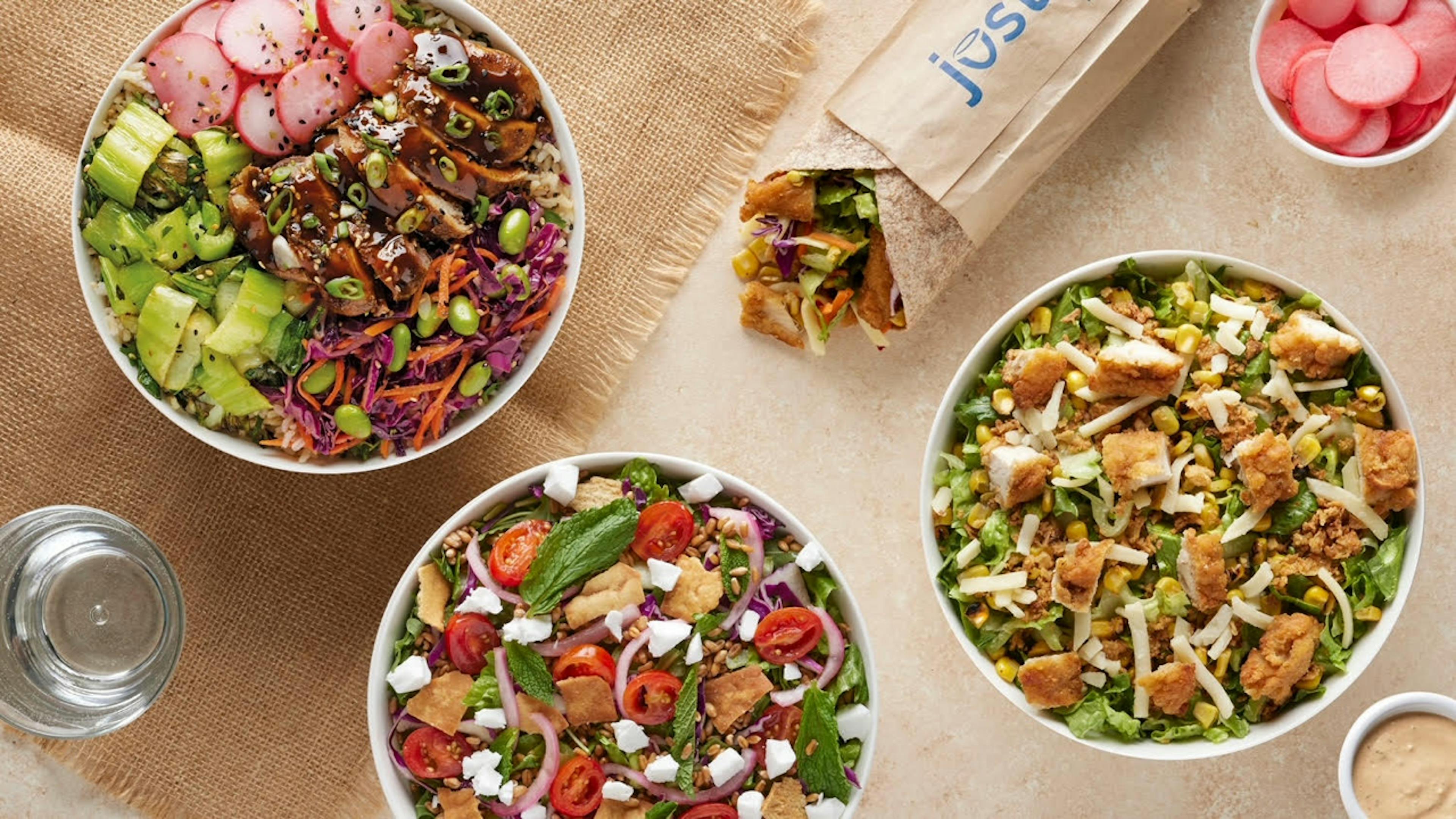 Image of three salads and a sandwich from Just Salad sitting on a table