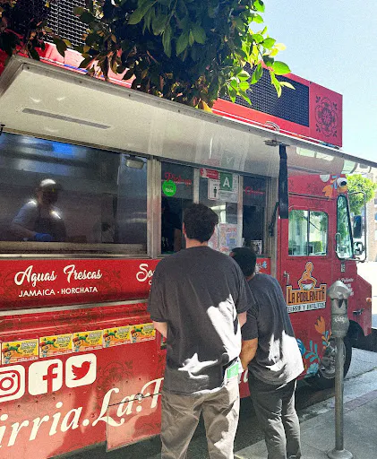 Customers waiting at a red food truck. 