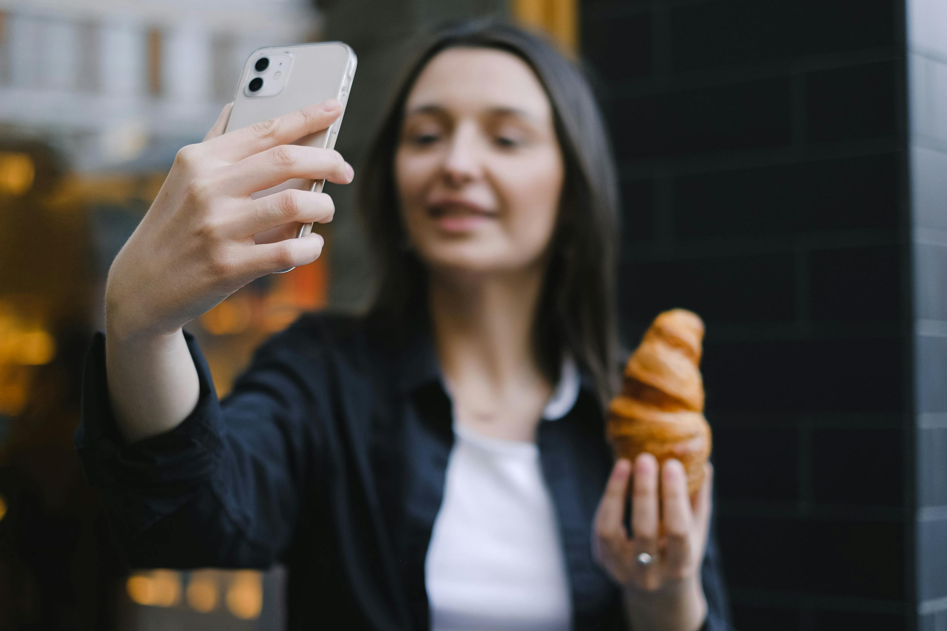 Influencer holding a croissant from a local cafe. 