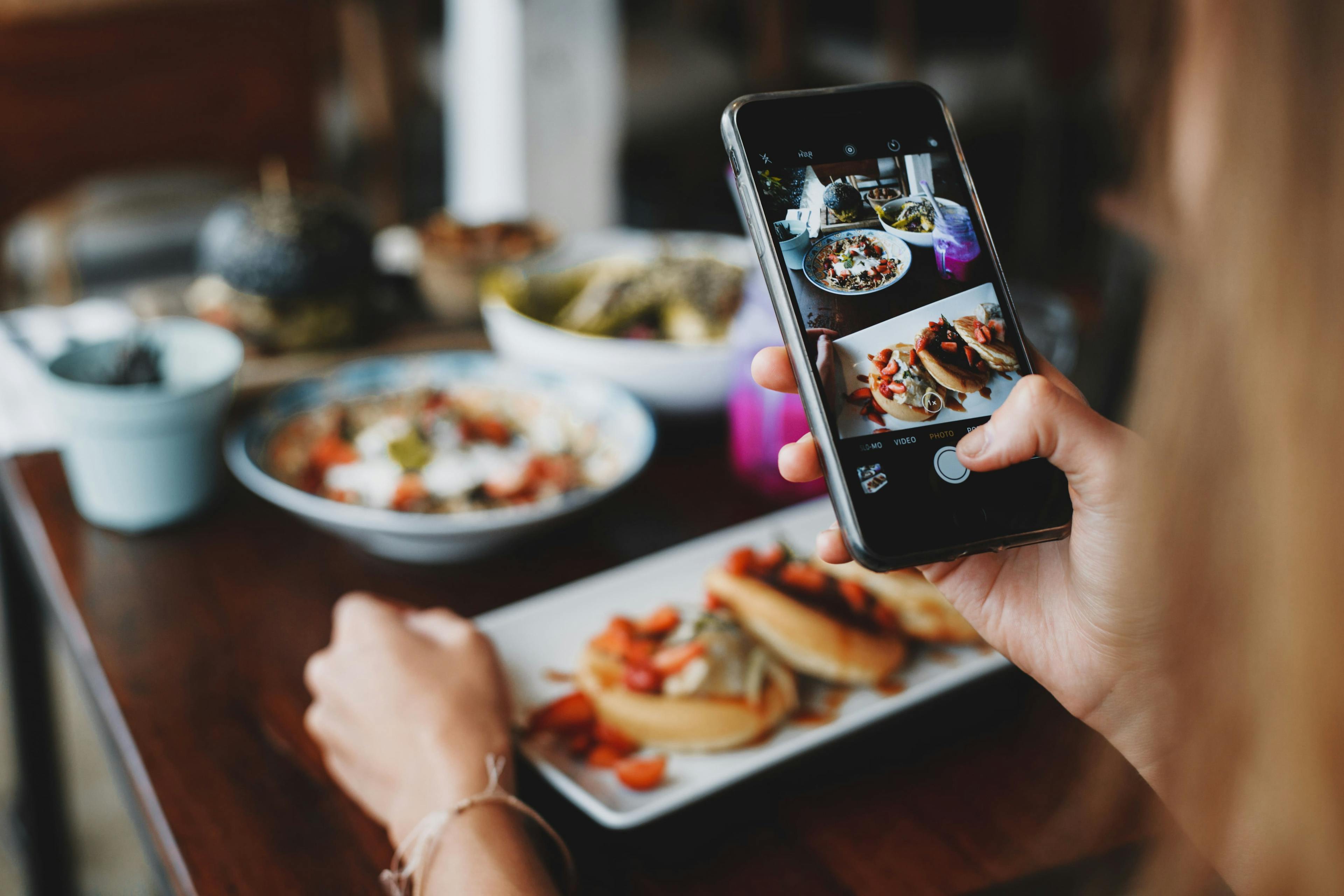 Image of someone eating at a restaurant and taking a photo of their plate before digging in