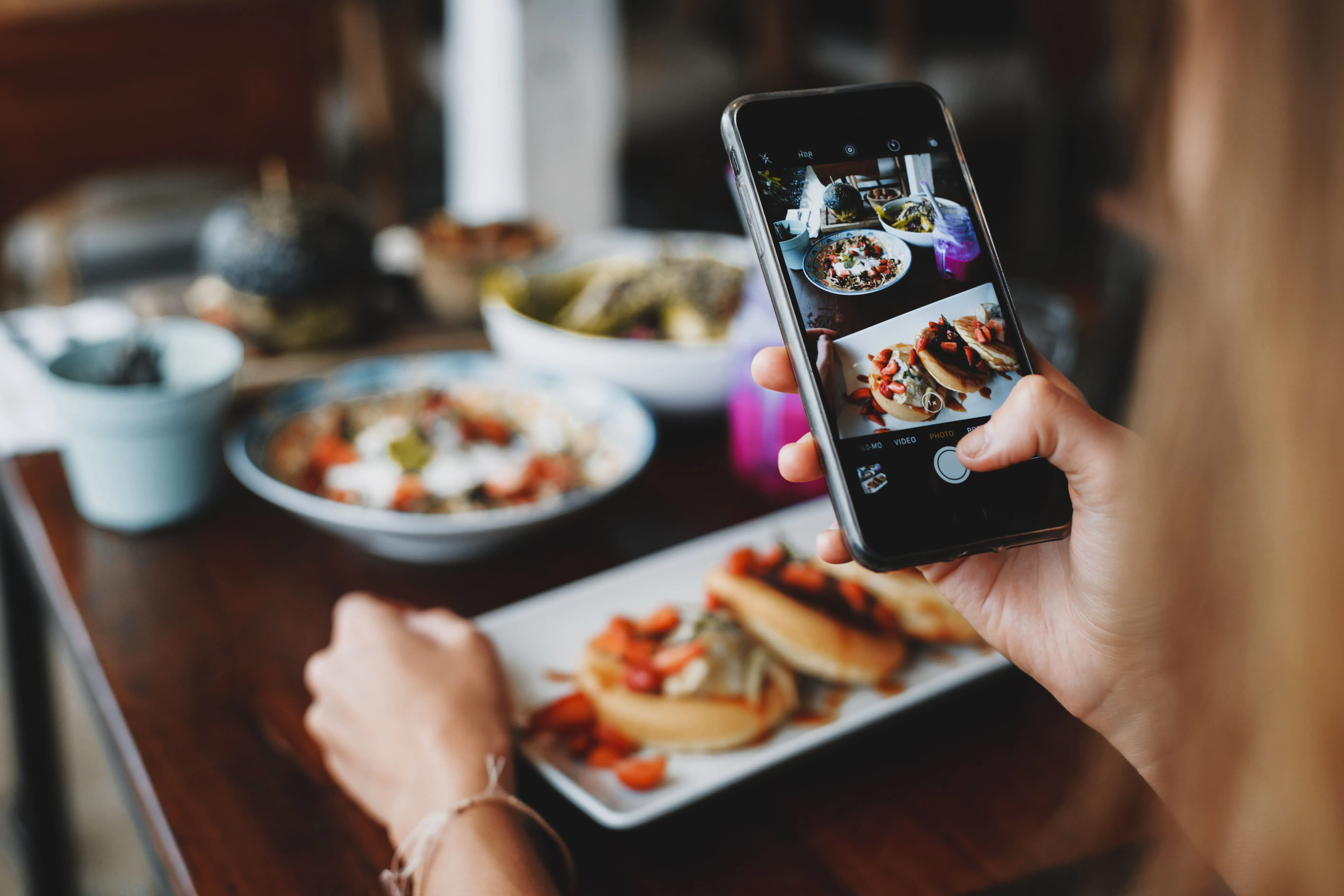 Image of someone eating at a restaurant and taking a photo of their plate before digging in