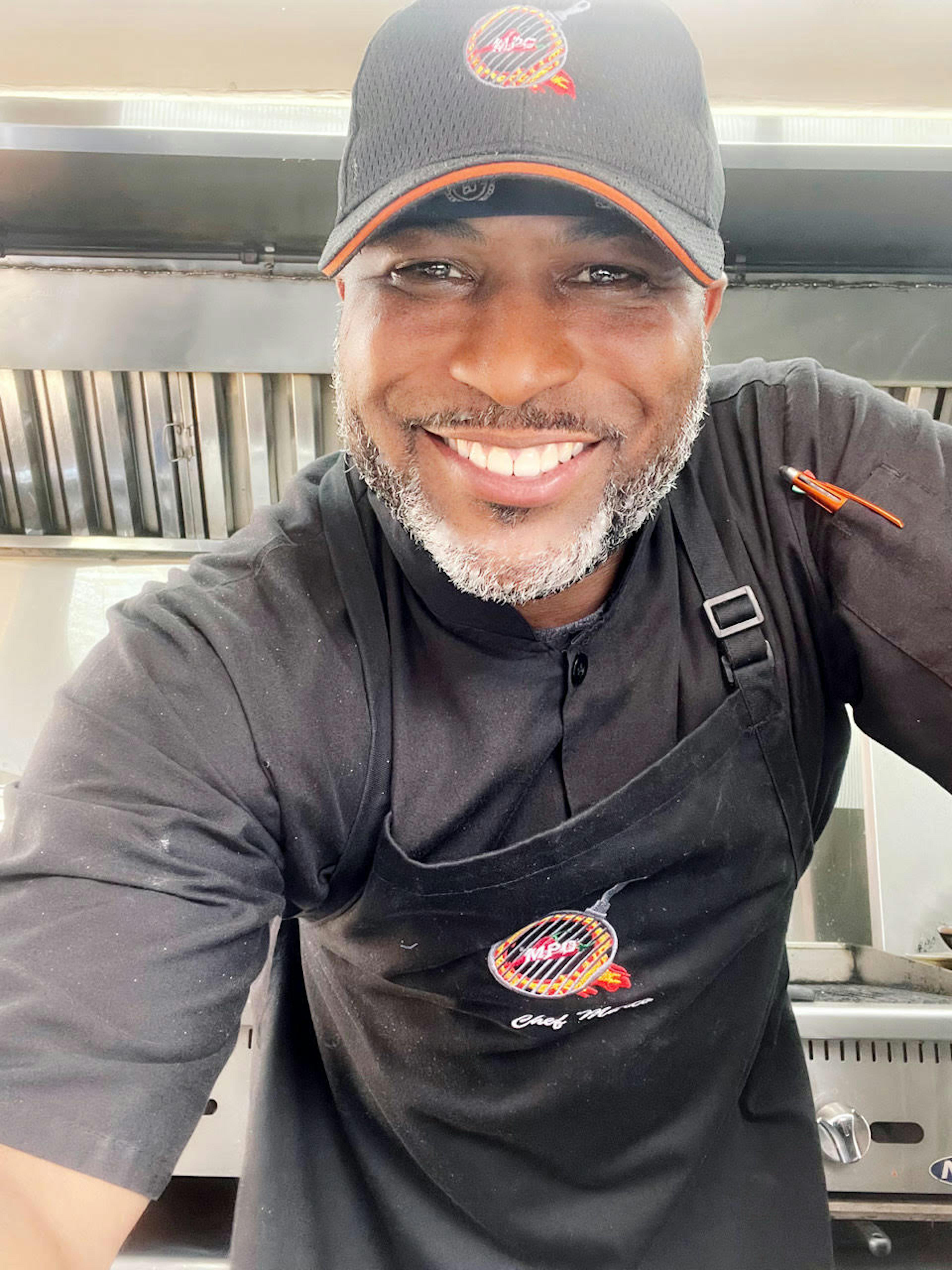 Image of Marco's Pepper Grill owner, Marcus Flakes, smiling while working in his food truck