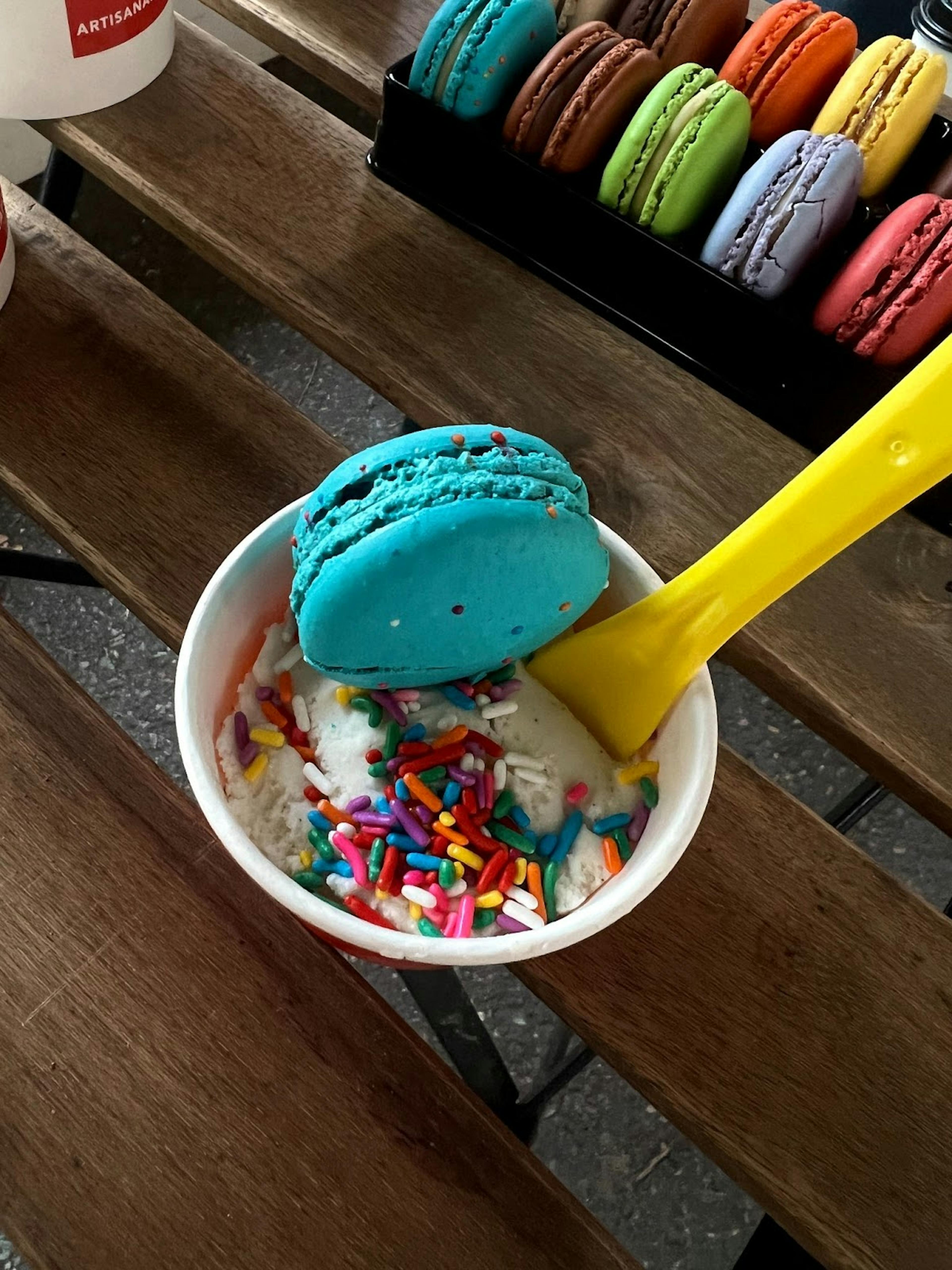 Image of a cup of Dolce Brooklyn gelato with sprinkles and a macaron on top