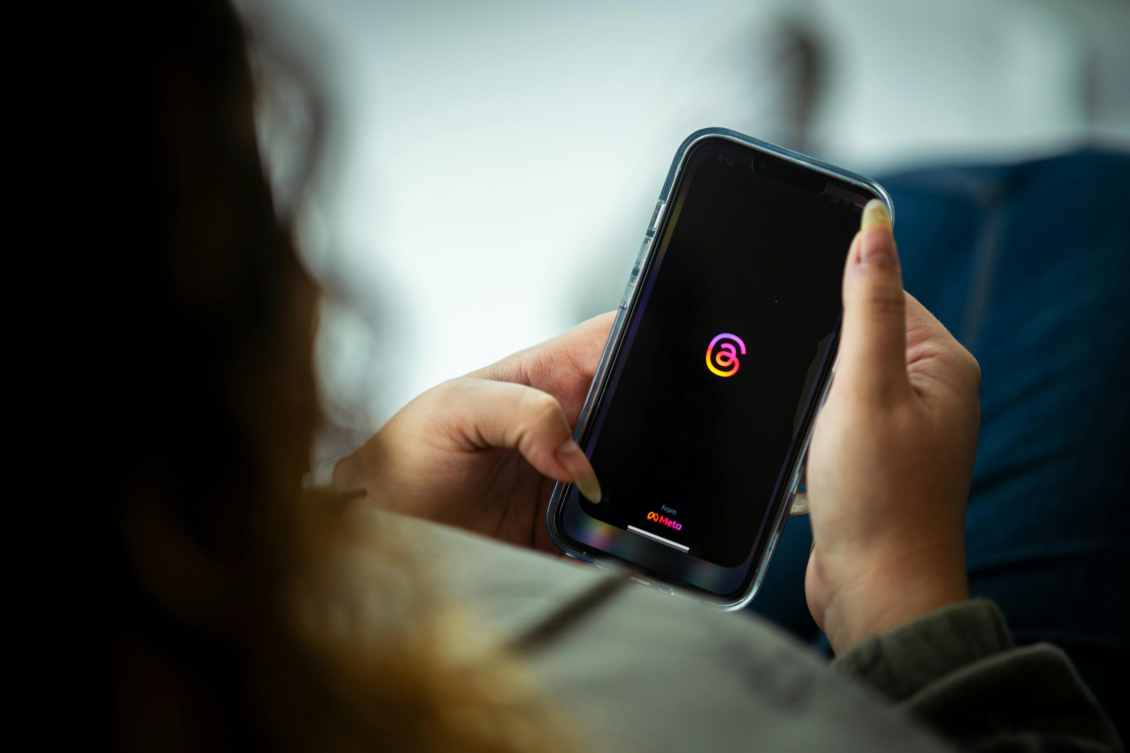 Woman looking at the Threads app on her phone. 