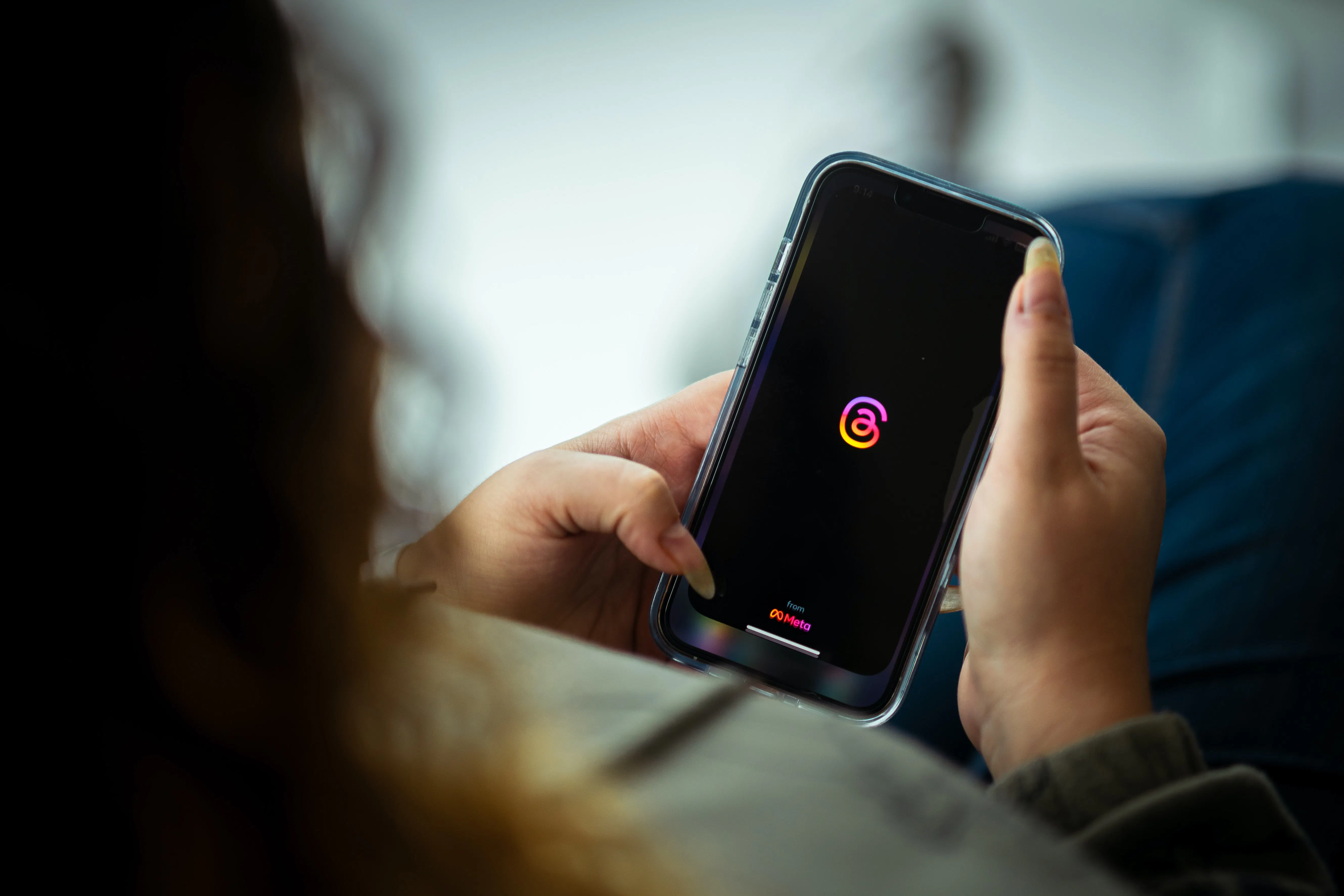 Woman looking at the Threads app on her phone.