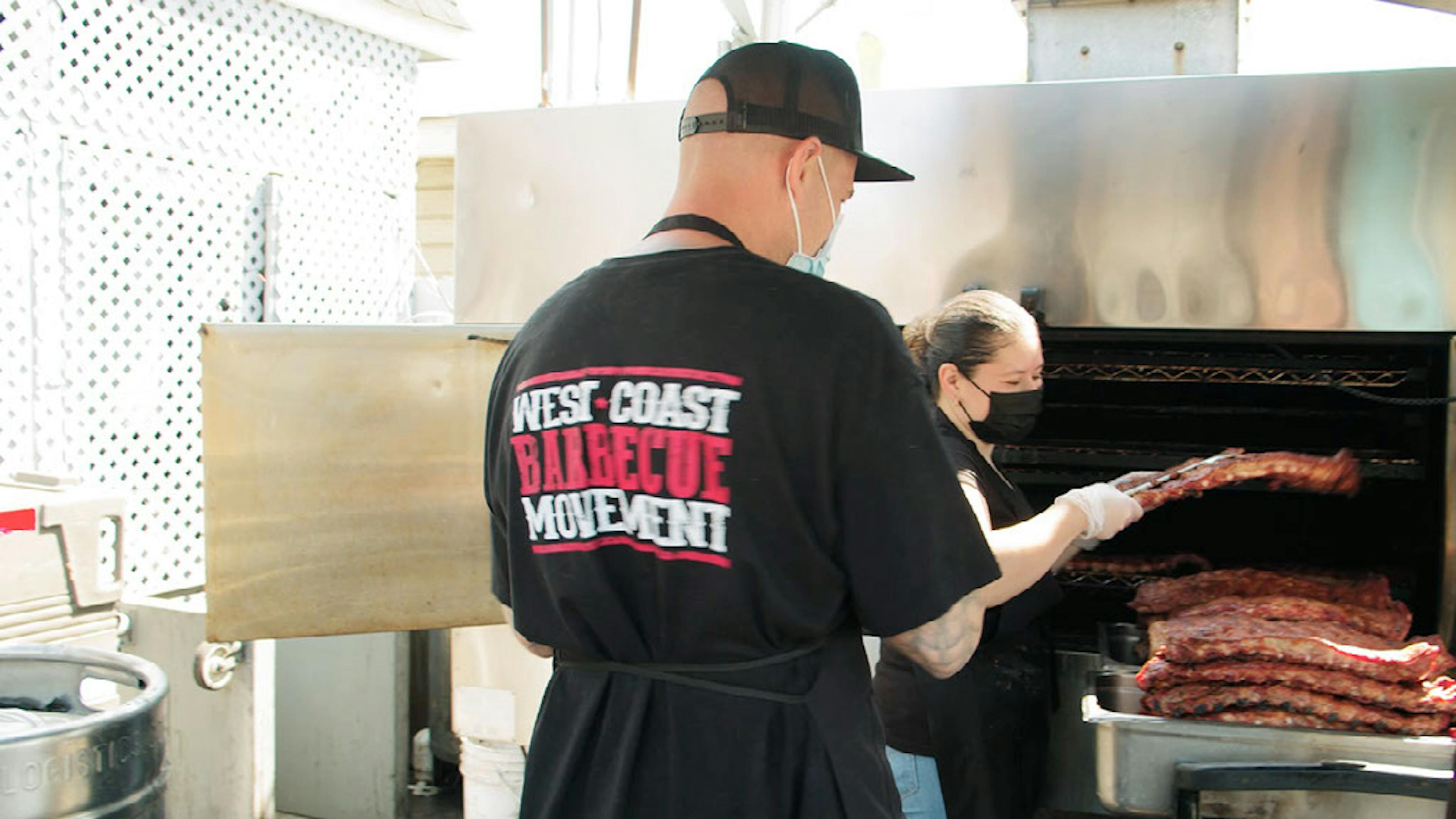 Image of Cali BBQ employee smoking ribs in a smoker