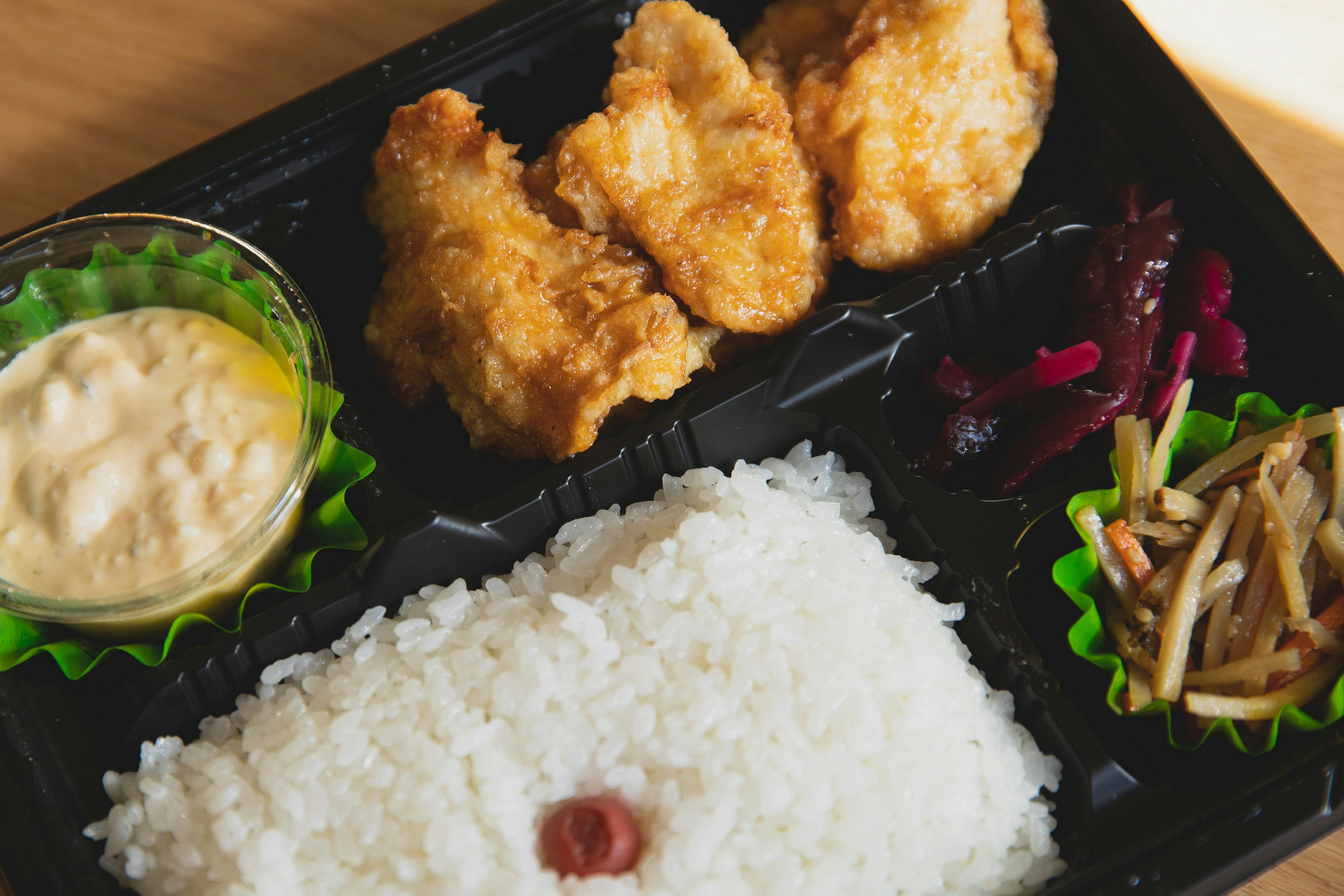 Image of a perfectly packed delivery meal with rice, dumplings and more