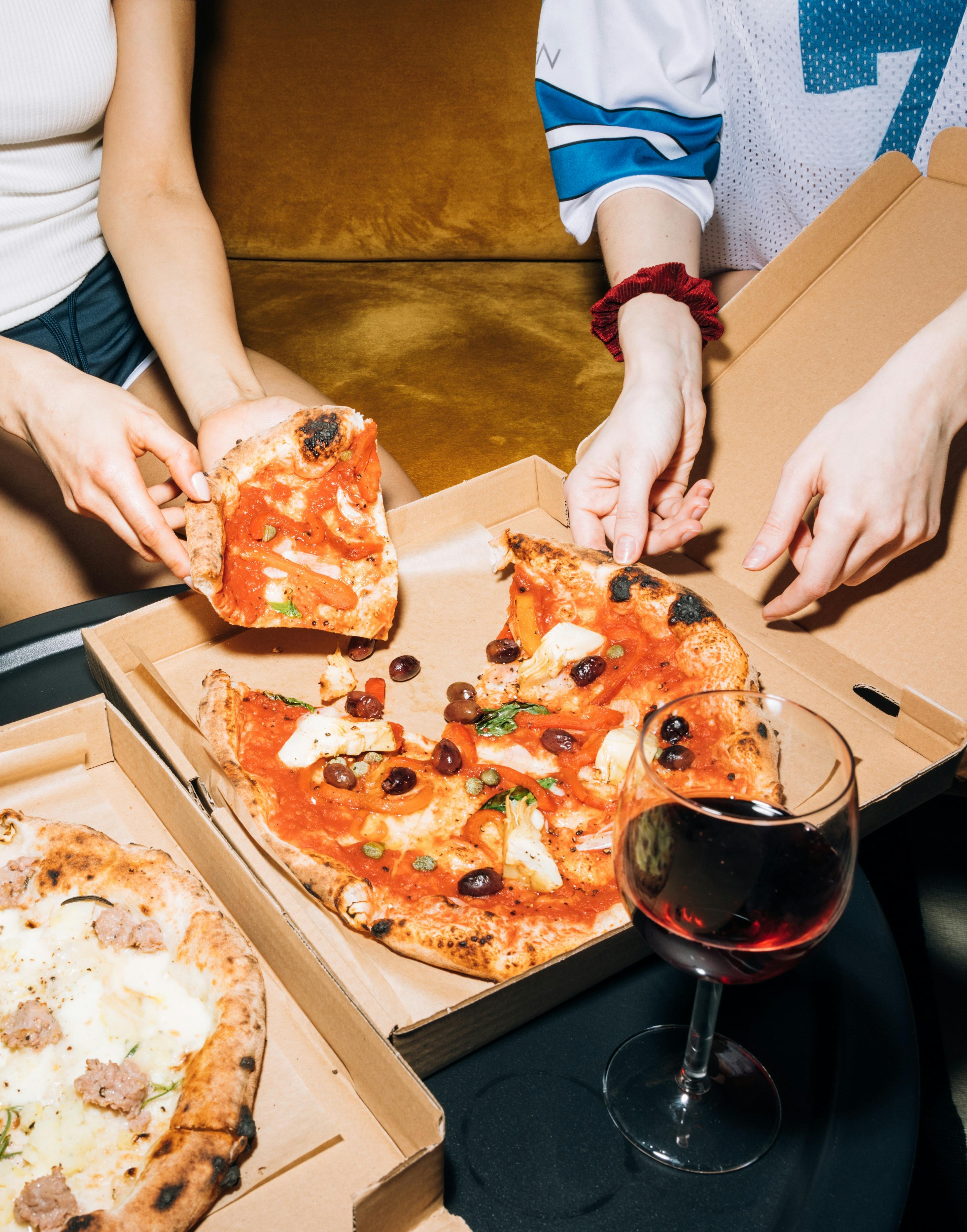 Image of a group of friends eating a pizza from a delivery box