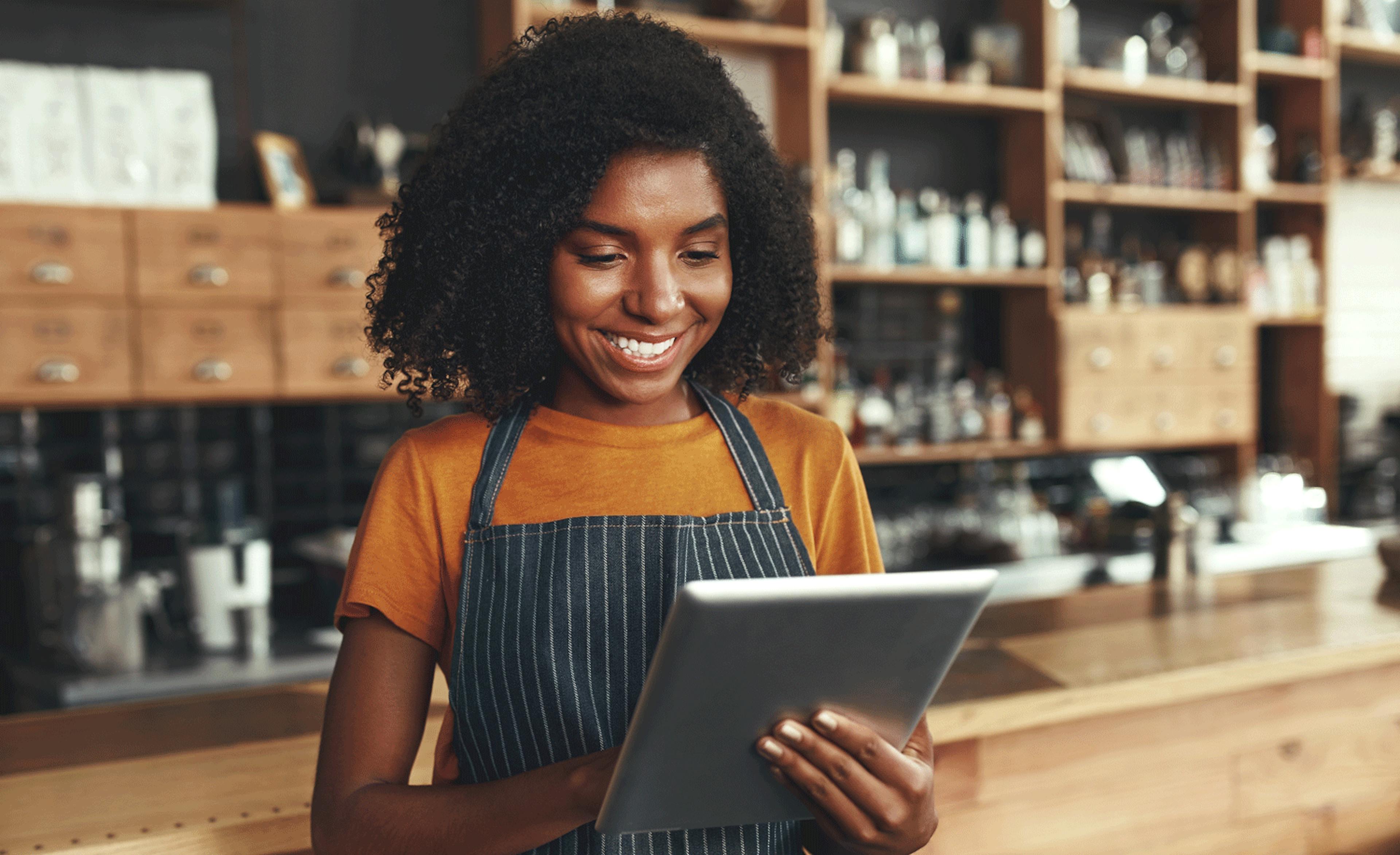 Image of a restaurant employee smiling while looking at a delivery tablet