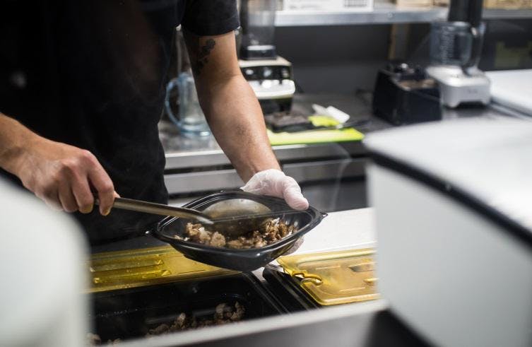 Image of restaurant employee preparing a bowl on the line