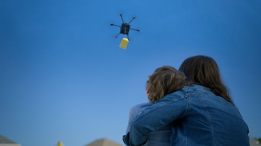 Image of a drone dropping off food delivery to a couple