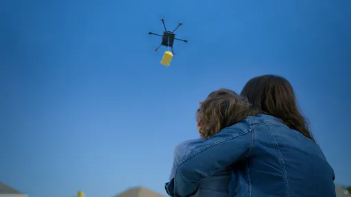 Image of a drone dropping off food delivery to a couple