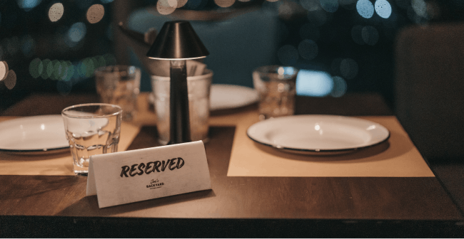 Image of a "reserved" tag sitting on top of a table at a restaurant