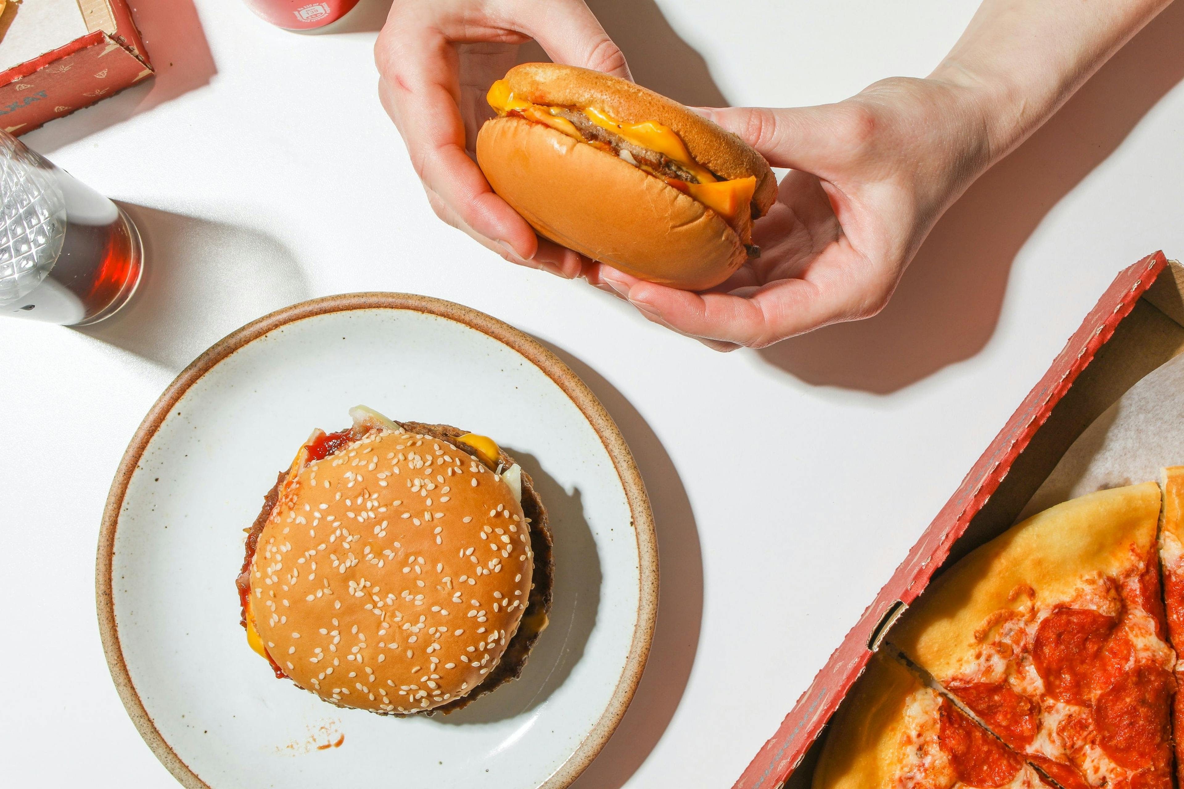 Image of a fast-food cheeseburger, fish sandwich, and pizza