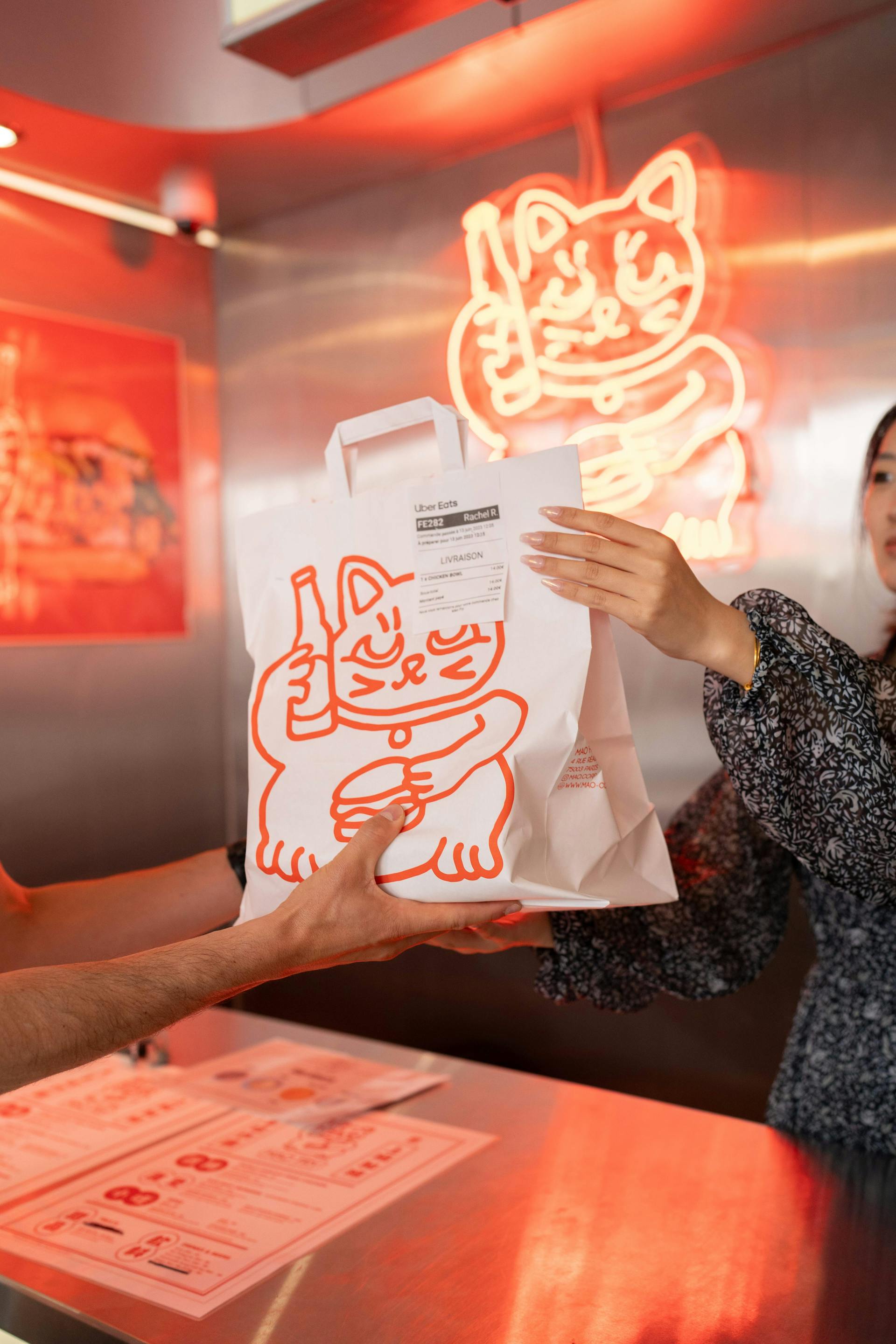 Image of restaurant employee in a trendy restaurant handing a delivery order off to a courier