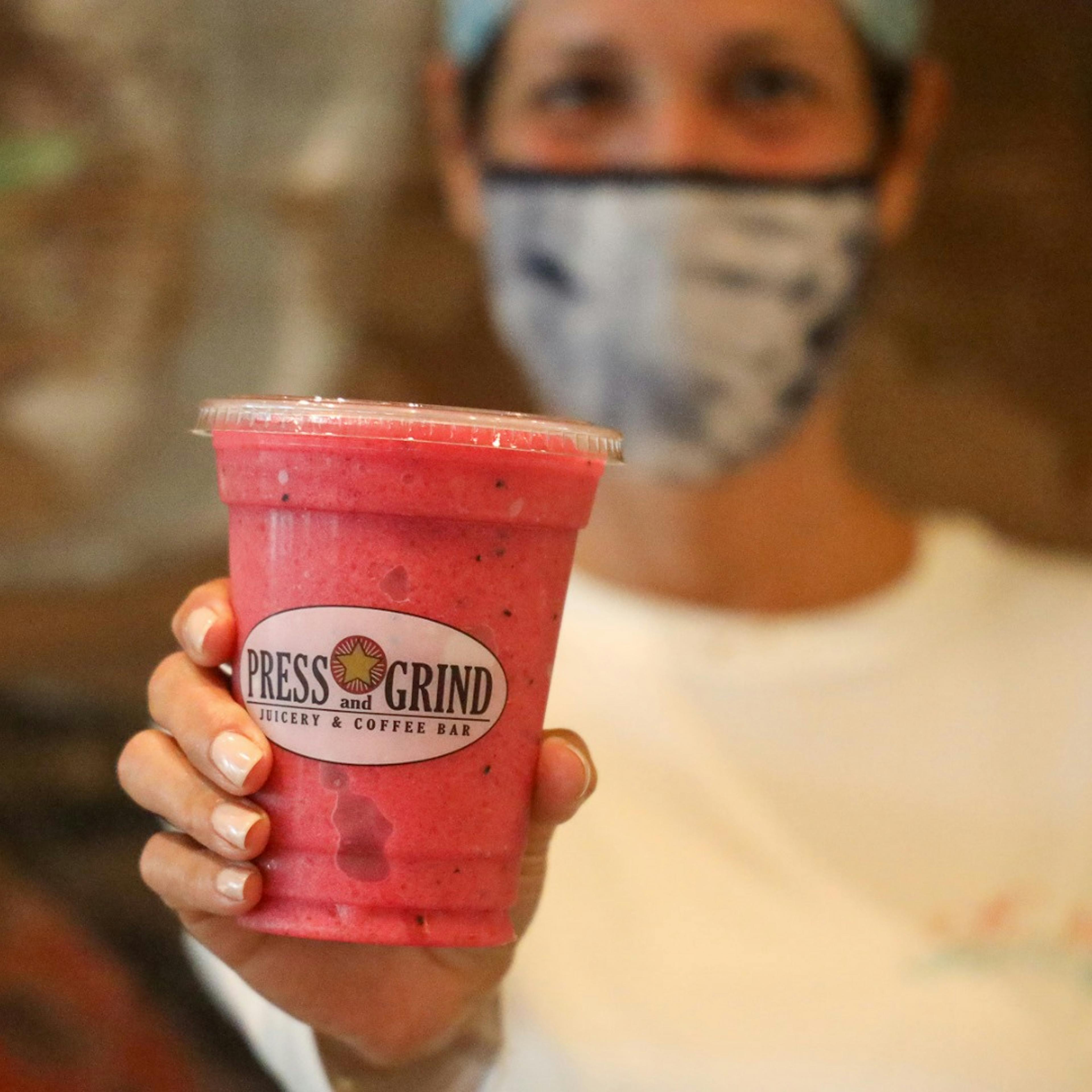 Press & Grind customer holding out a pink smoothie