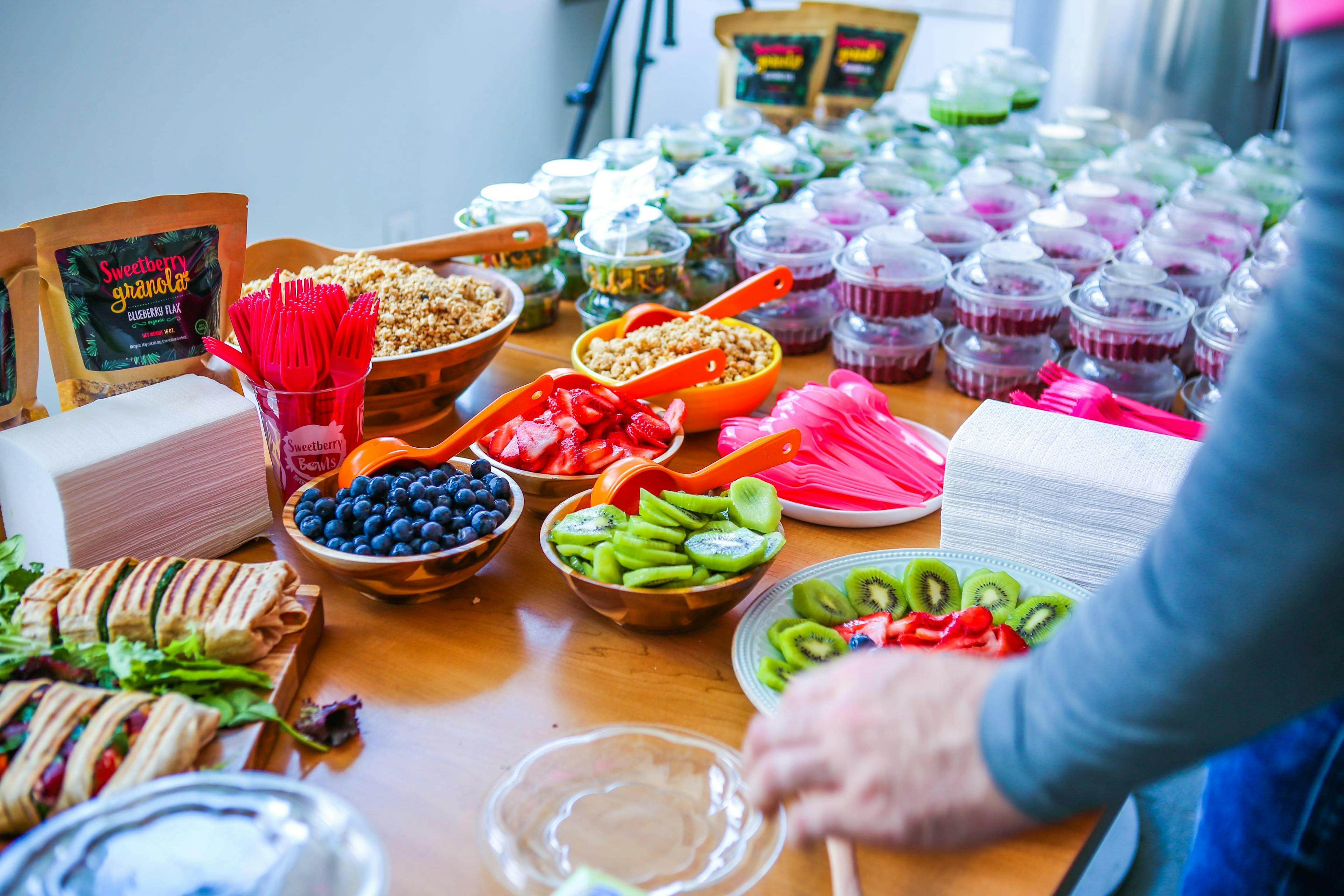 Image of table covered with multiple acai bowls, fruit toppings and more