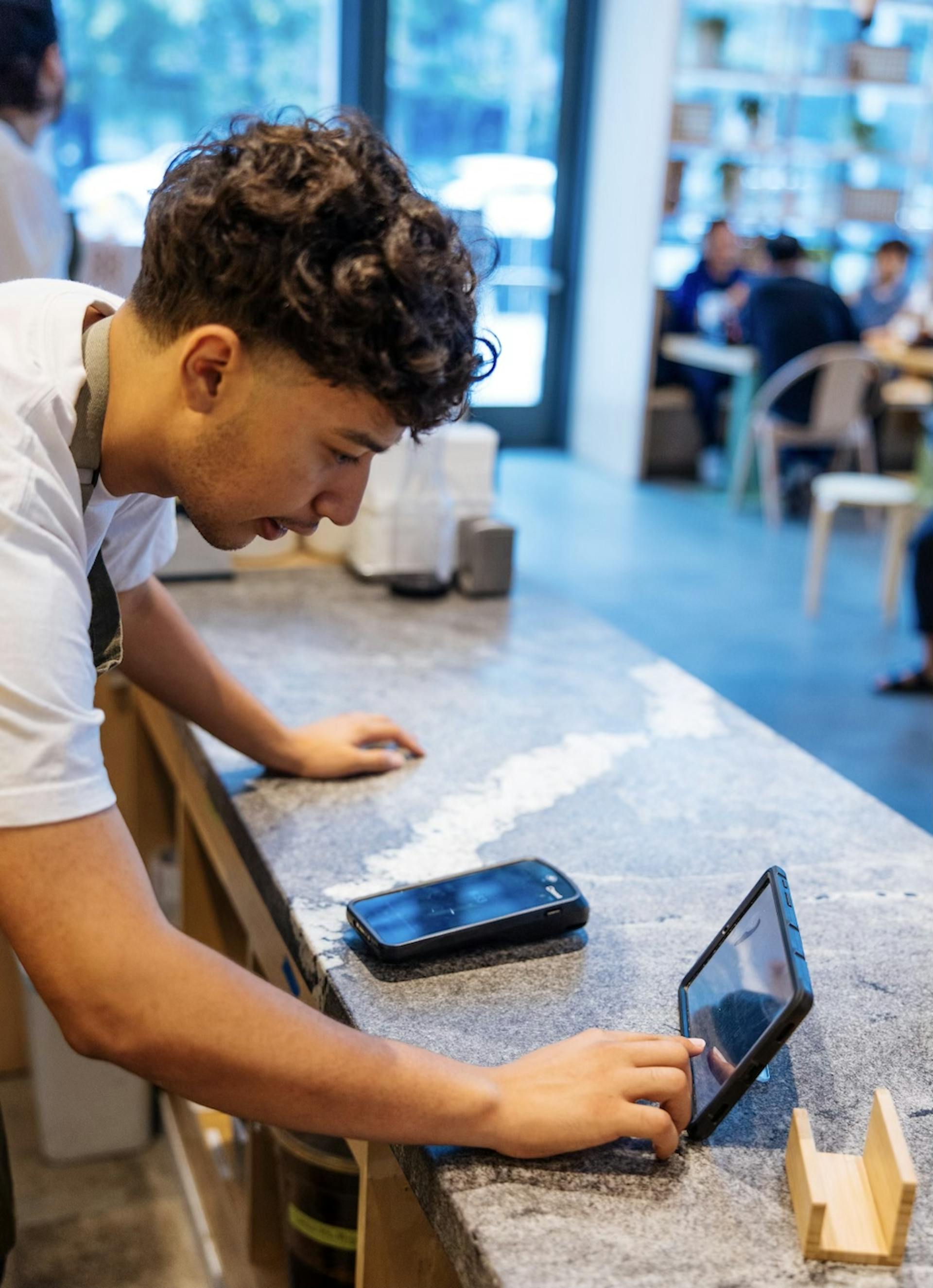 Image of a restaurant employee managing orders on the tablet in his front-of-house
