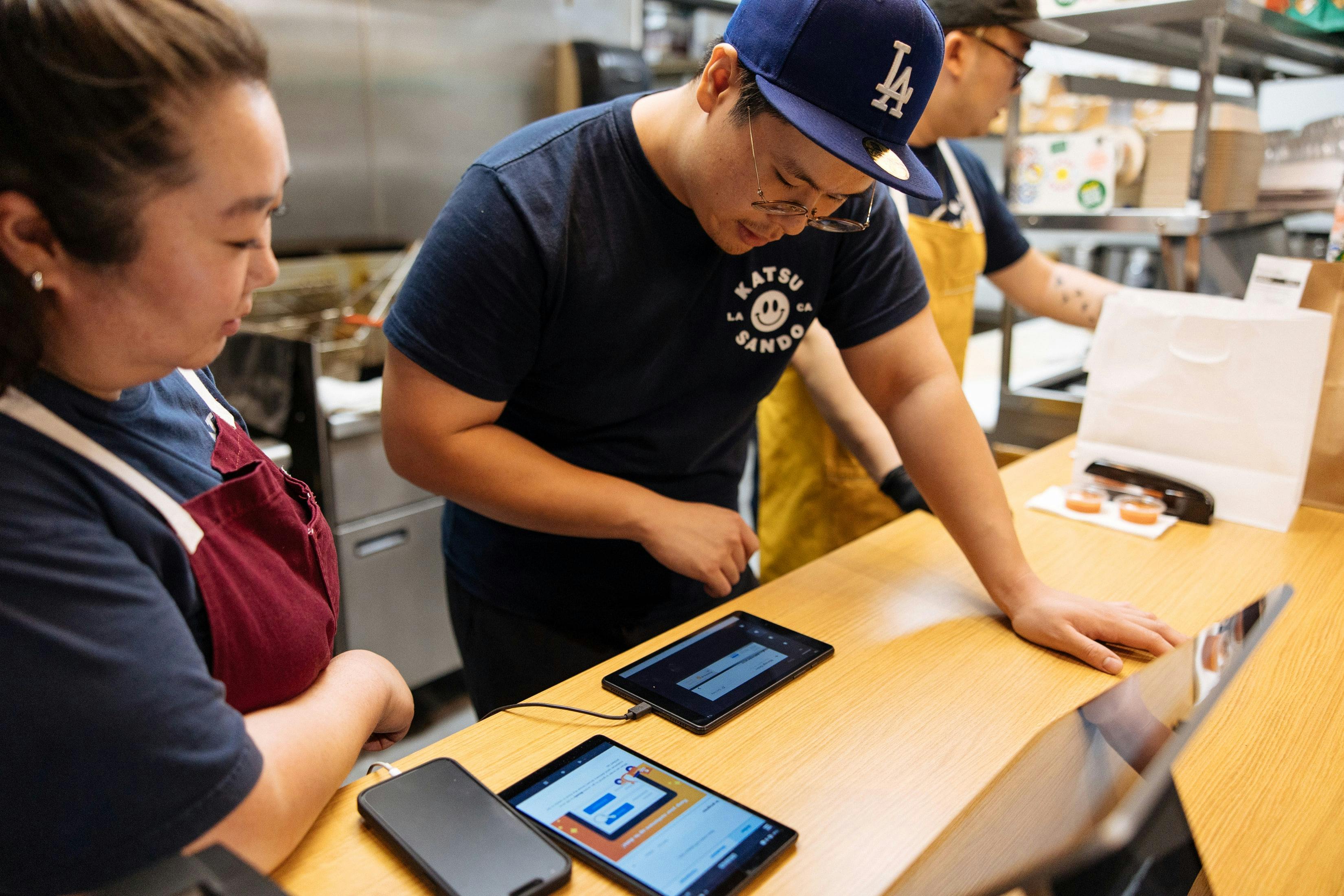 Image of restaurant employees managing incoming orders on tablets
