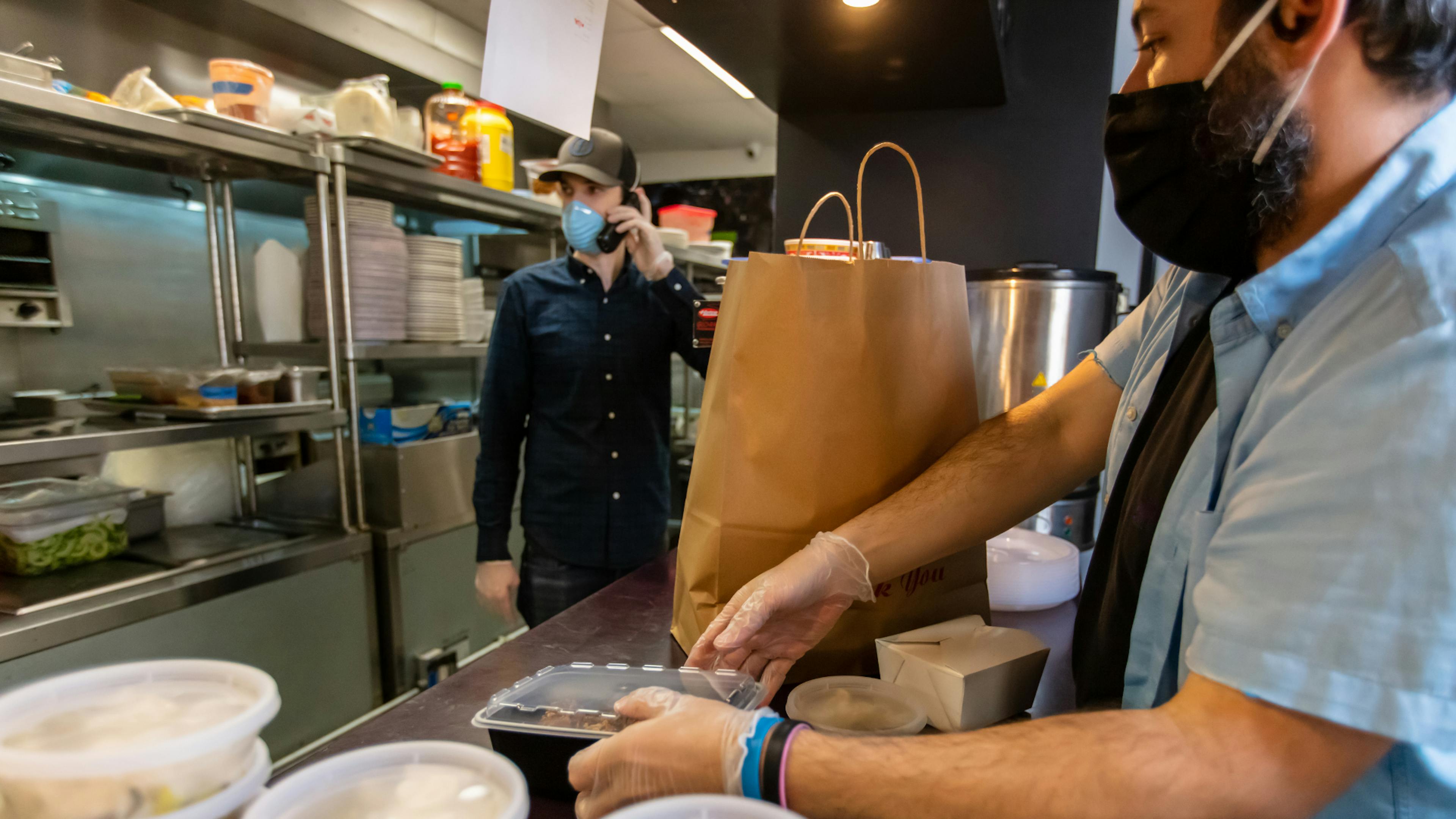 Image of restaurant staff packing orders while on the phone