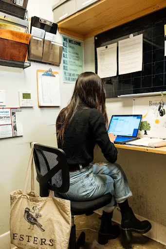 Image of a restaurant employee working on her computer in the back-of-house
