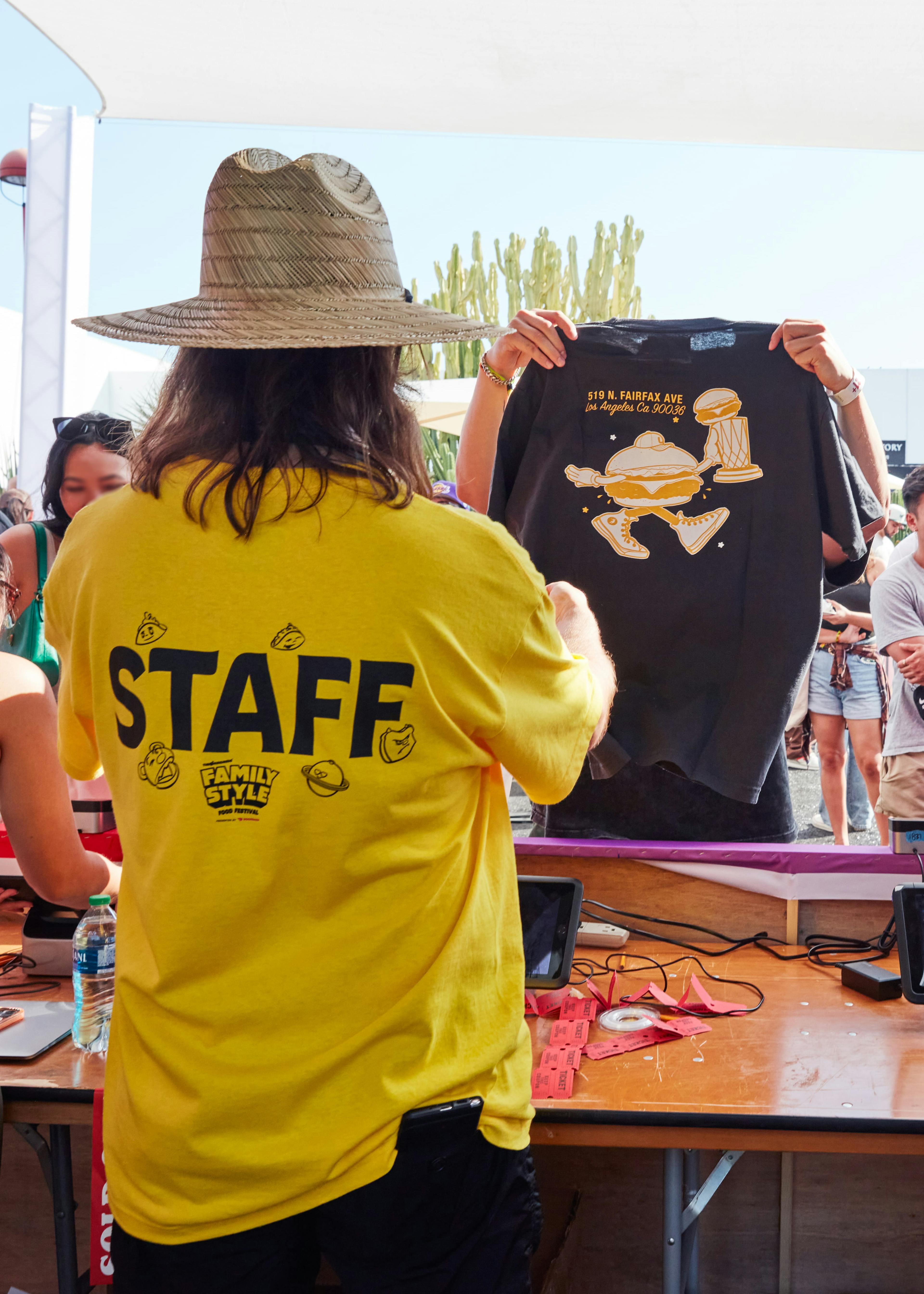 Image of staff member at Family Style food festival selling a cool t-shirt with a burger on it to a young person