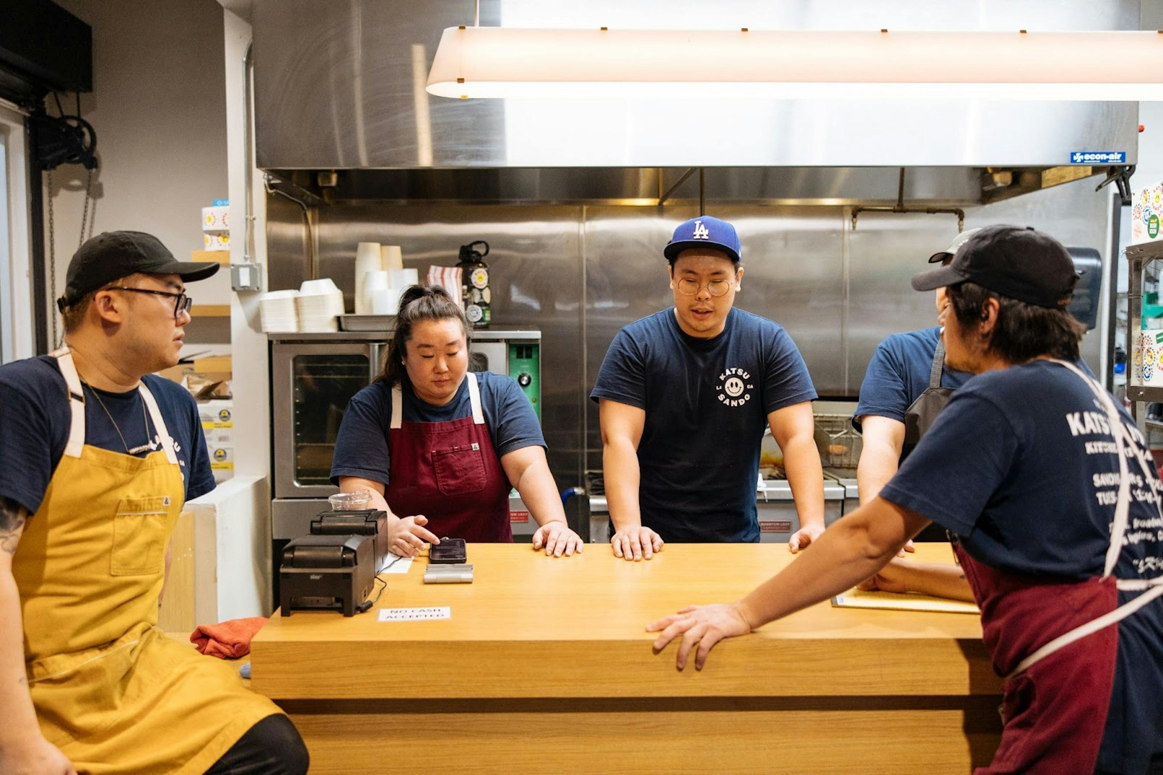 Image of a 4 restaurant staff members standing around an island strategizing