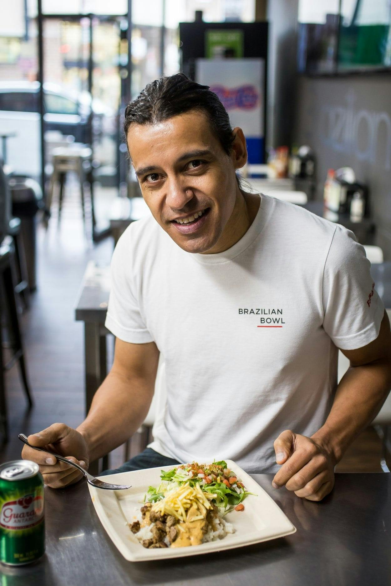 Image of Tony Ferreira eating a plate of Brazilian food in his restaurant, Brazilian Bowl